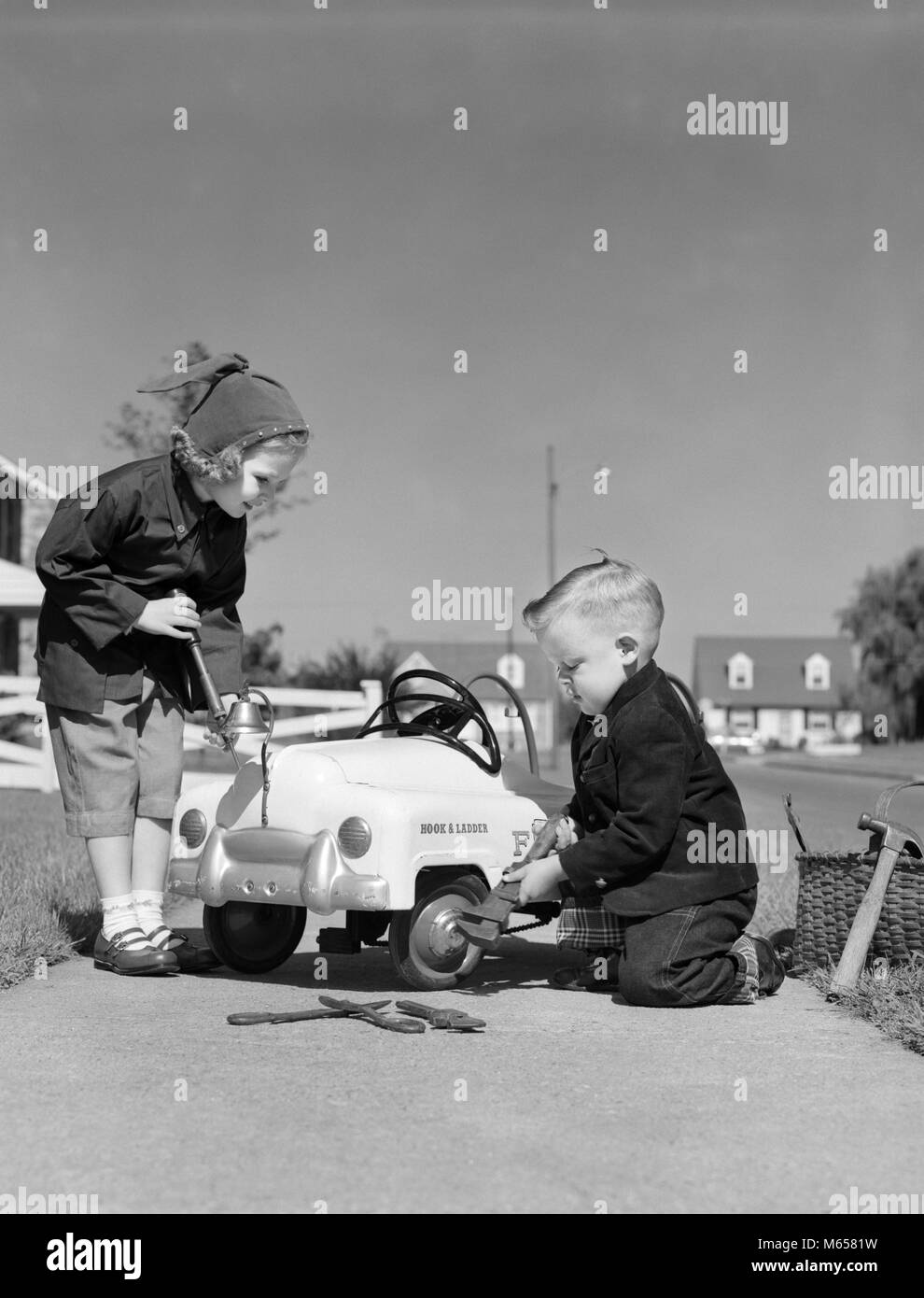 1930s TWO CHILDREN BOY AND A GIRL WORKING FIXING SERVICING A TOY PEDDLE CAR AUTOMOBILE - j5811 HAR001 HARS LIFESTYLE FEMALES BROTHERS HOME LIFE COPY SPACE PEOPLE CHILDREN FRIENDSHIP FULL-LENGTH INSPIRATION AUTOMOBILE SIBLINGS CONFIDENCE FIXING SISTERS TRANSPORTATION NOSTALGIA TOGETHERNESS GOALS SUCCESS 5-6 YEARS HAPPINESS CUSTOMER SERVICE AUTOS KNOWLEDGE PROGRESS RECREATION LABOR PRIDE EMPLOYMENT SIBLING REPAIRING CONNECTION COOPERATION AUTOMOBILES VEHICLES EMPLOYEE JUVENILES MALES SERVICING B&W BLACK AND WHITE CAUCASIAN ETHNICITY CONCENTRATION LABORING OCCUPATIONS OLD FASHIONED PEDDLE CAR Stock Photo