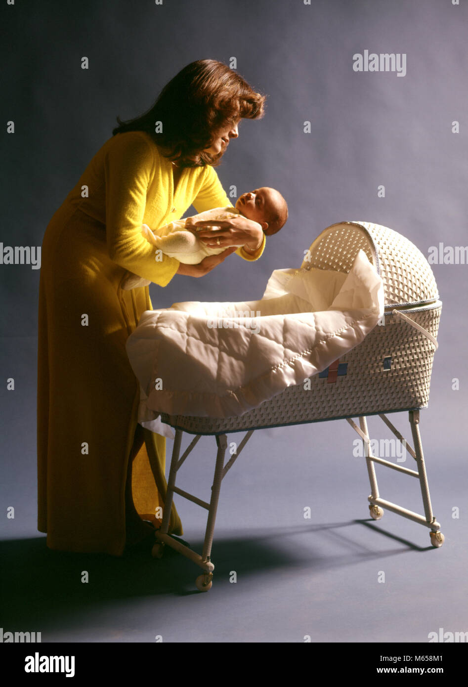 1970s MOTHER WEARING YELLOW ROBE PUTTING BABY CHILD TO SLEEP IN WHITE WOVEN WICKER BASSINET - kb12365 HAR001 HARS BEDTIME CAUCASIAN SONS JOY LIFESTYLE PARENTING FEMALES STUDIO SHOT ROBE HOME LIFE COPY SPACE HALF-LENGTH DAUGHTERS WICKER CARING INDOORS NOSTALGIA TOGETHERNESS 0-1 YEARS 20-25 YEARS 25-30 YEARS SINGLE OBJECT HAPPINESS PROTECTION MOMS CRADLE BASSINET GROWTH CONNECTION CAREGIVER BABY BOY 1-6 MONTHS JUVENILES MALES MID-ADULT MID-ADULT WOMAN NIGHTTIME WOVEN BABY GIRL BASSINETTE CAUCASIAN ETHNICITY GOOD NIGHT OLD FASHIONED PUTTING TO BED TUCKING IN Stock Photo