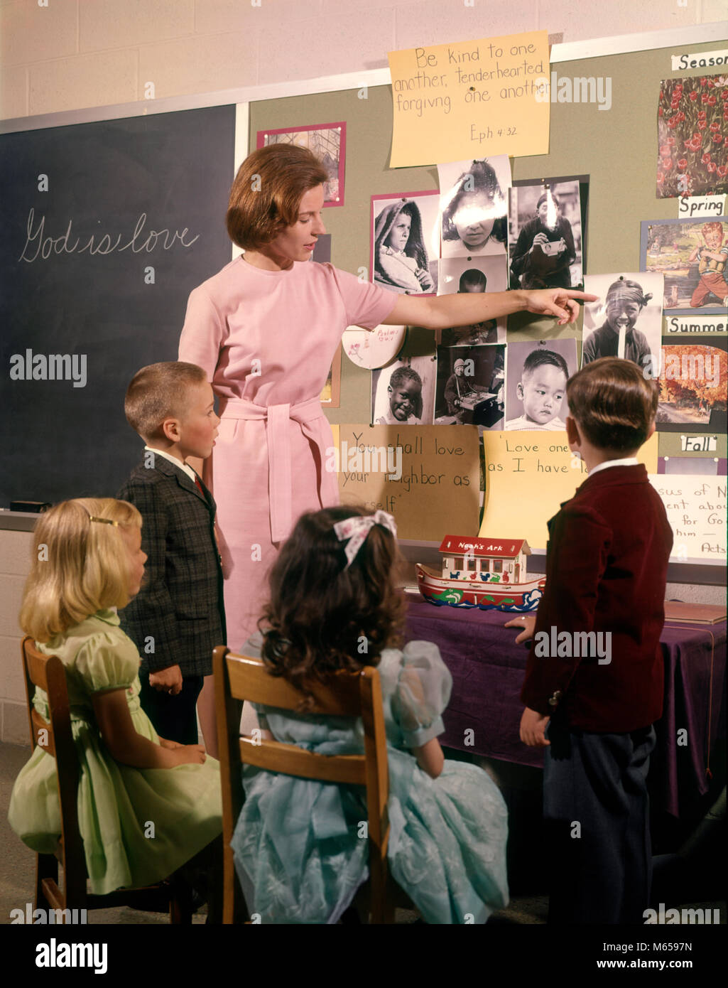 1960s WOMAN SUNDAY SCHOOL TEACHER POINTING AT BULLETIN BOARD WITH TWO BOYS AND TWO GIRLS IN CLASS - kc2354 HAR001 HARS RELIGION FEMALES 5 SUNDAY GROWNUP COPY SPACE HALF-LENGTH LADIES GROWN-UP INDOORS NOSTALGIA TOGETHERNESS 25-30 YEARS 30-35 YEARS 7-9 YEARS SCHOOLS 5-6 YEARS RELIGIOUS COOPERATION SMALL GROUP OF PEOPLE CHURCHES FAITH JUVENILES MALES MID-ADULT MID-ADULT WOMAN BELIEF BULLETIN BOARD CAUCASIAN ETHNICITY DEVOUT GOD IS LOVE OLD FASHIONED PERSONS SUNDAY SCHOOL Stock Photo