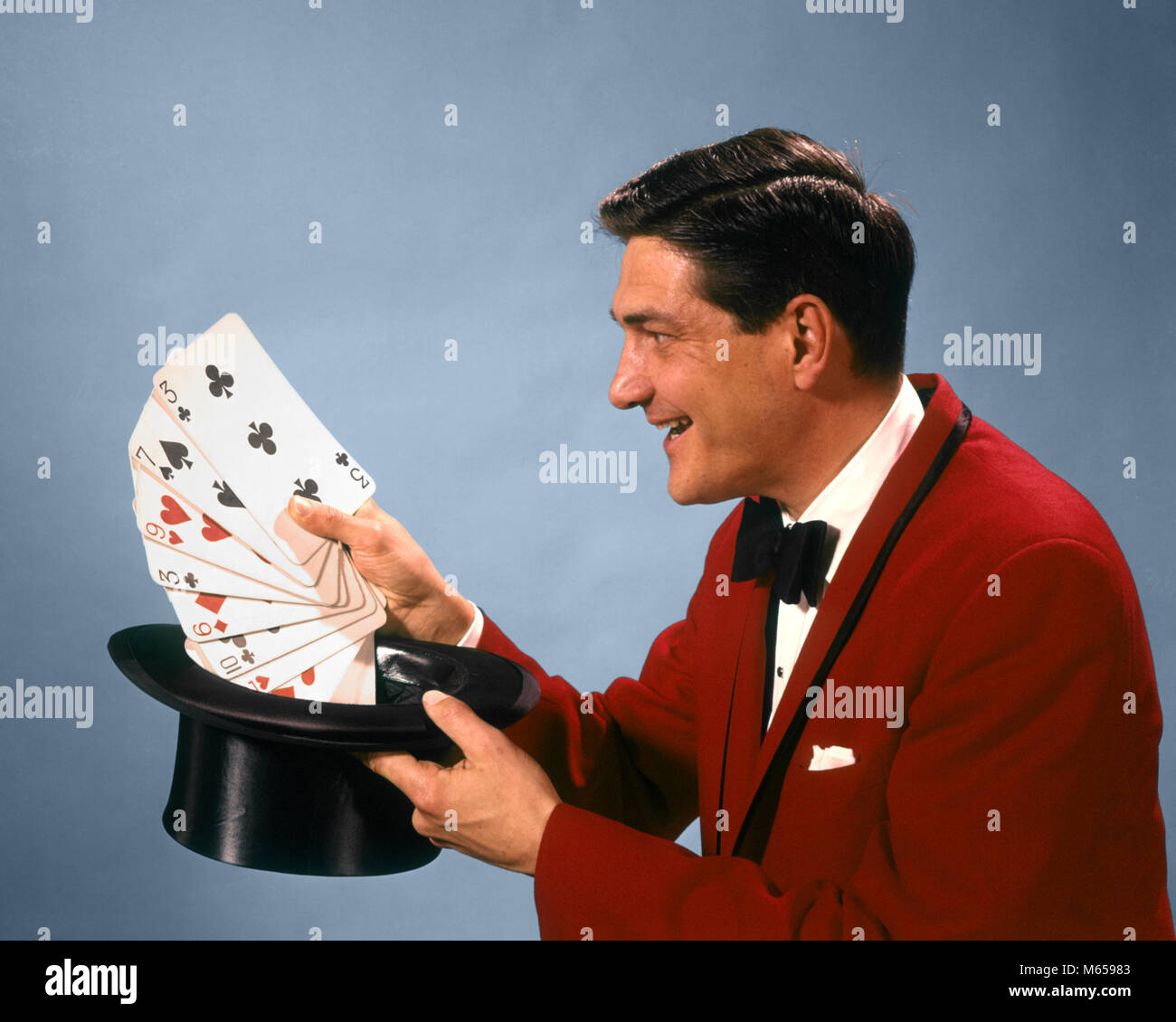 1960s 1970s MAN MAGICIAN RED SUIT BOW TIE PULLING OVERSIZE PLAYING CARDS OUT OF TOP HAT - kc2841 HAR001 HARS 30-35 YEARS 35-40 YEARS MAGICIANS PEOPLE STORY ILLUSION MANUAL PERFORMER CHARACTERS EXCITEMENT OVERSIZE RED SUIT ENTERTAINER CONJURER SMALL GROUP OF OBJECTS BOW TIE MAGICAL LEGERDEMAIN MALES MID-ADULT MID-ADULT MAN PLAYING CARDS TOP HAT CAUCASIAN ETHNICITY DECK OF CARDS HAND OF CARDS OCCUPATIONS OLD FASHIONED PERSONS PRESTIDIGITATION SLEIGHT OF HAND Stock Photo