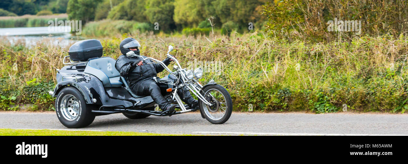 A motorised tricycle driven by a leather-clad biker in Devon. Stock Photo
