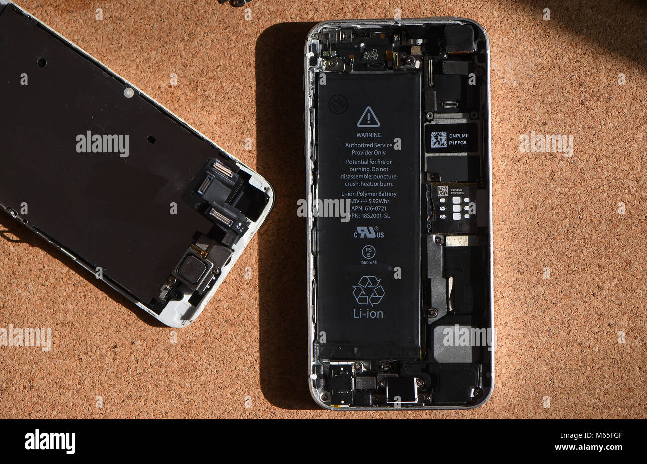 Home DIY replacement of a iPhone 5s battery showing phone opened with new and old battery and internals of phone. Stock Photo