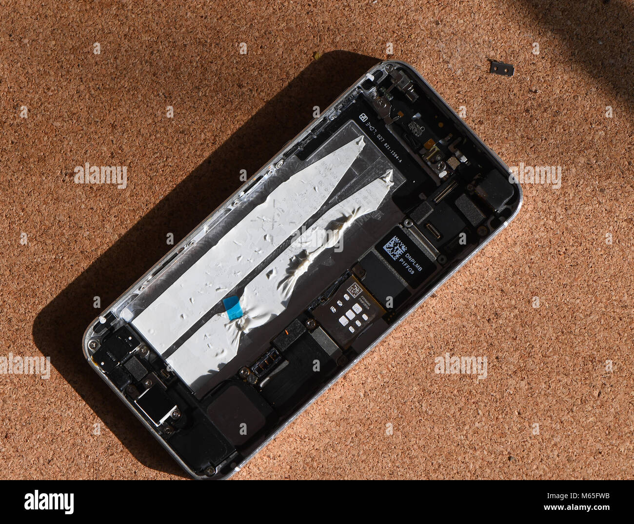 Home DIY replacement of a iPhone 5s battery showing phone opened with new and old battery and internals of phone. Stock Photo