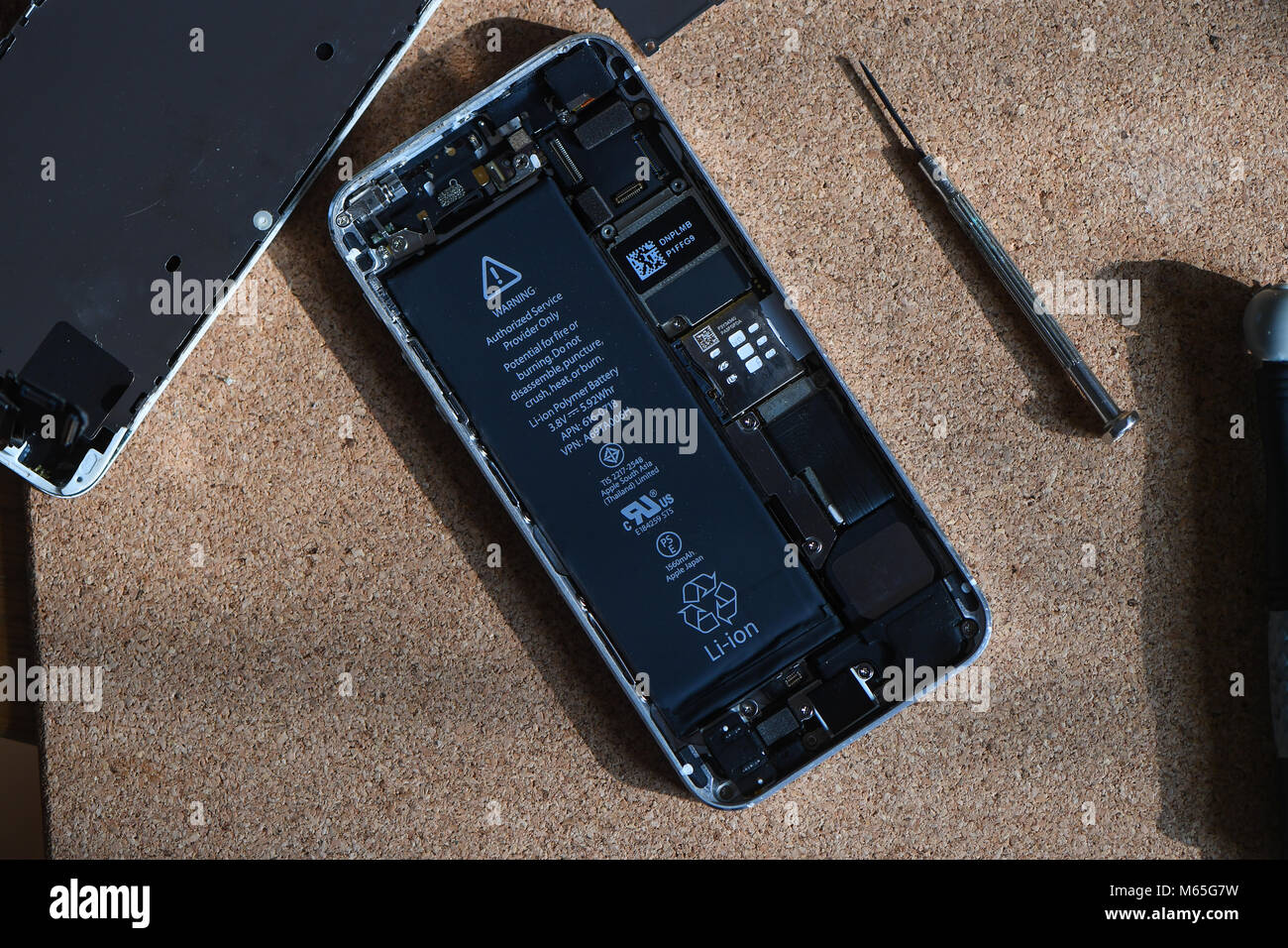 Home DIY replacement of a iPhone 5s battery showing phone opened with new and old battery and internals of phone. Stock Photo