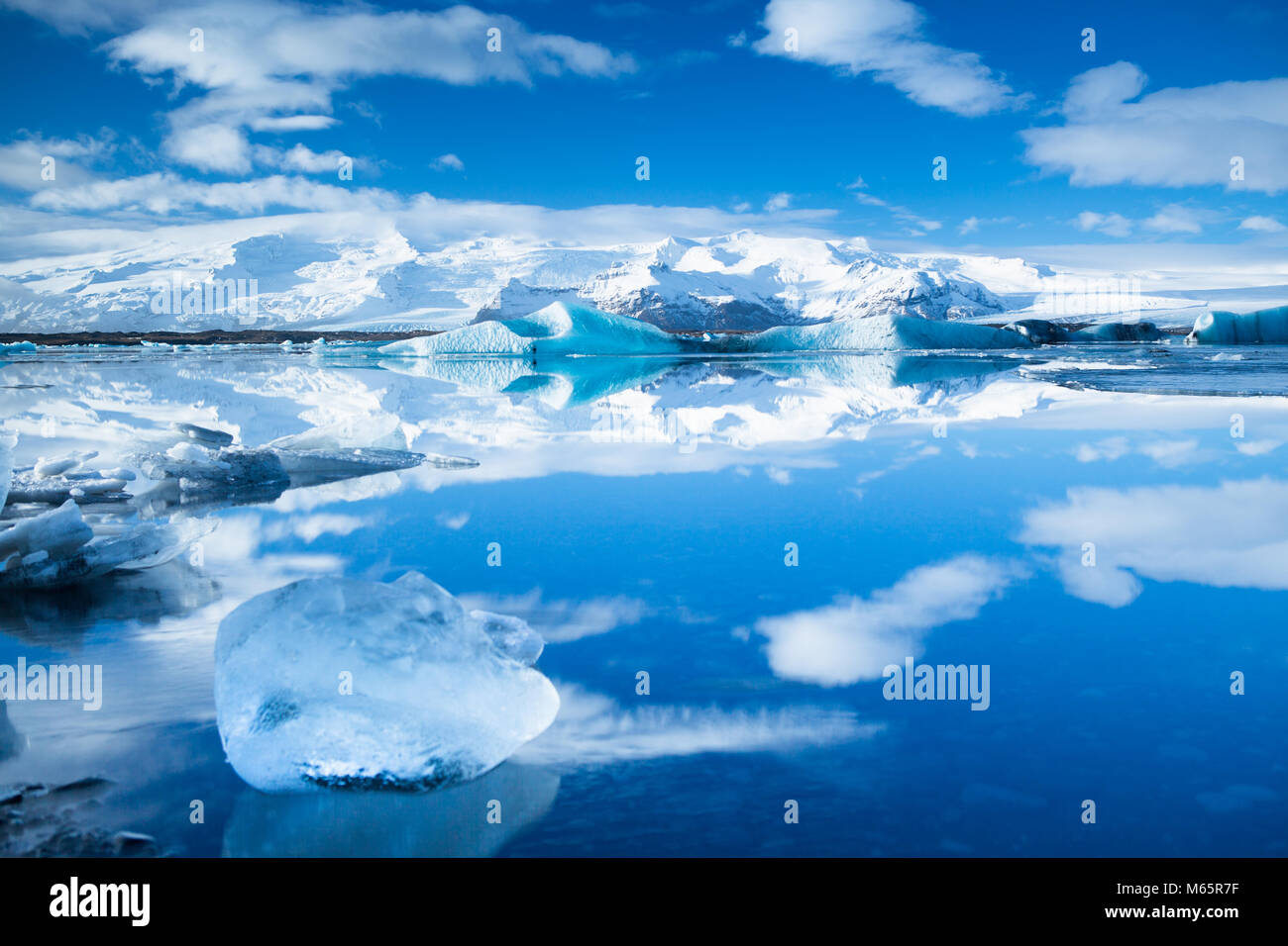 Perfect reflections and ice in lake in Iceland with blue sky and puffy clouds Stock Photo