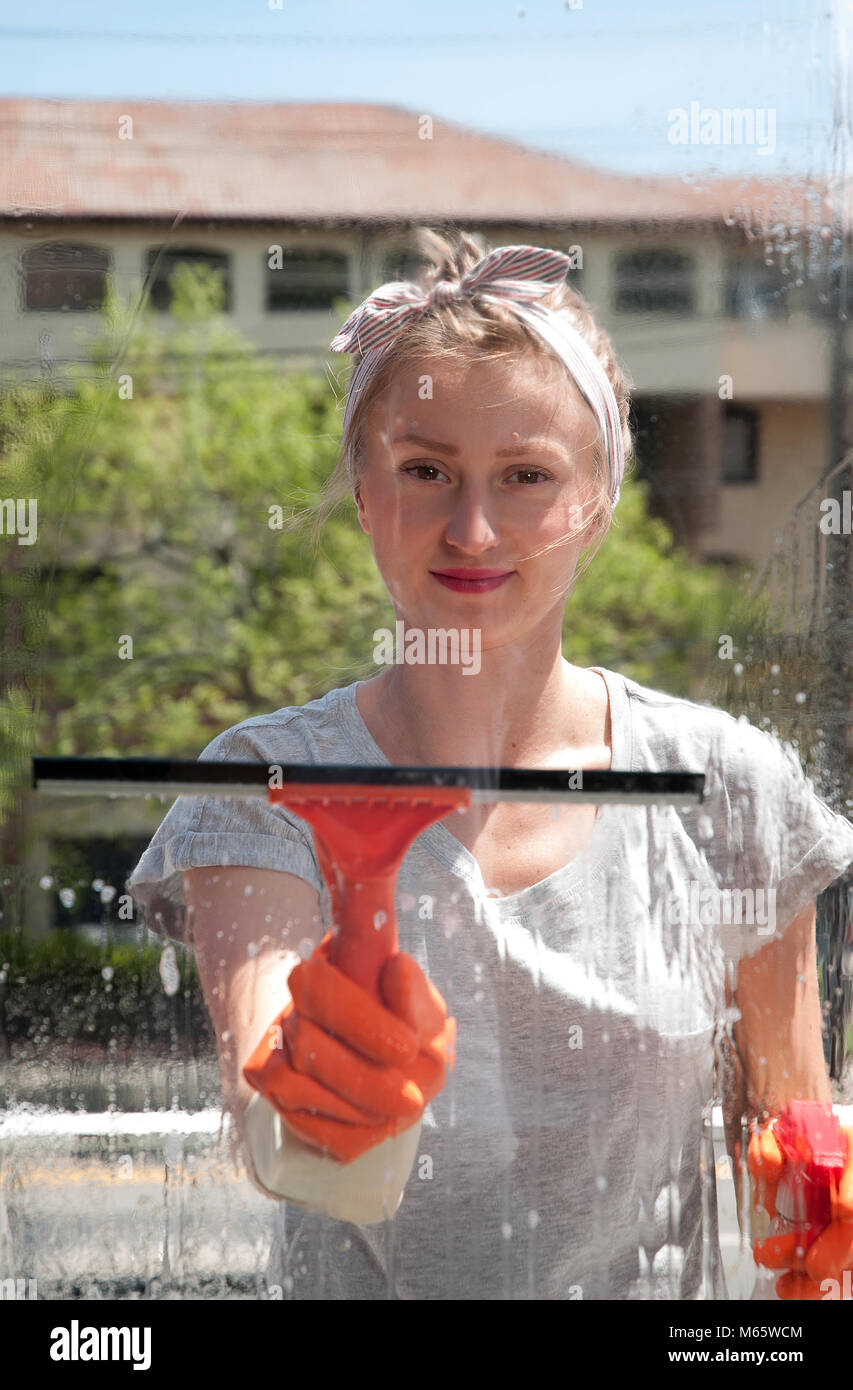 Cleaning woman washing windows using a squeegee to wash a window Stock