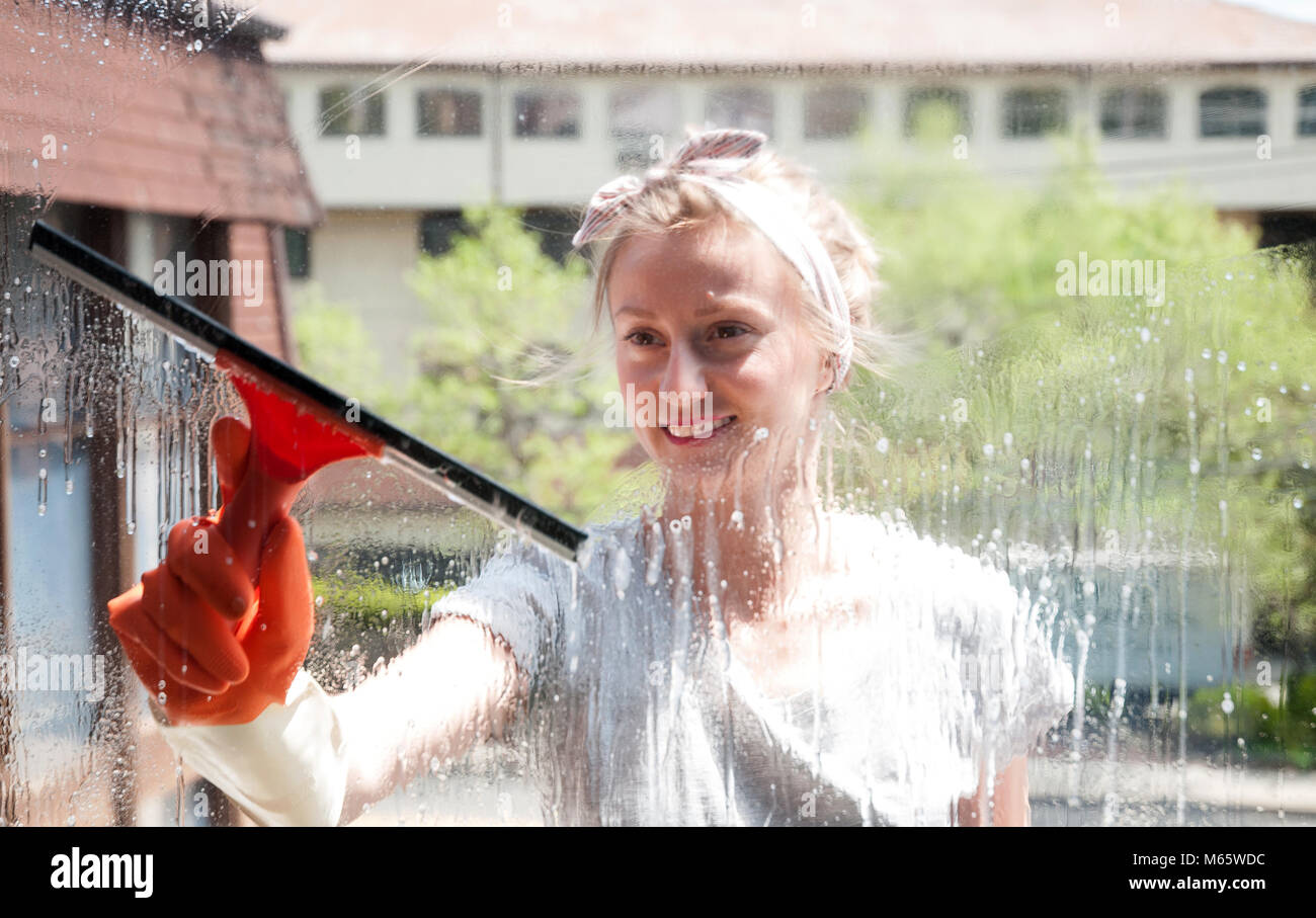 Cleaning woman washing windows using a squeegee to wash a window Stock