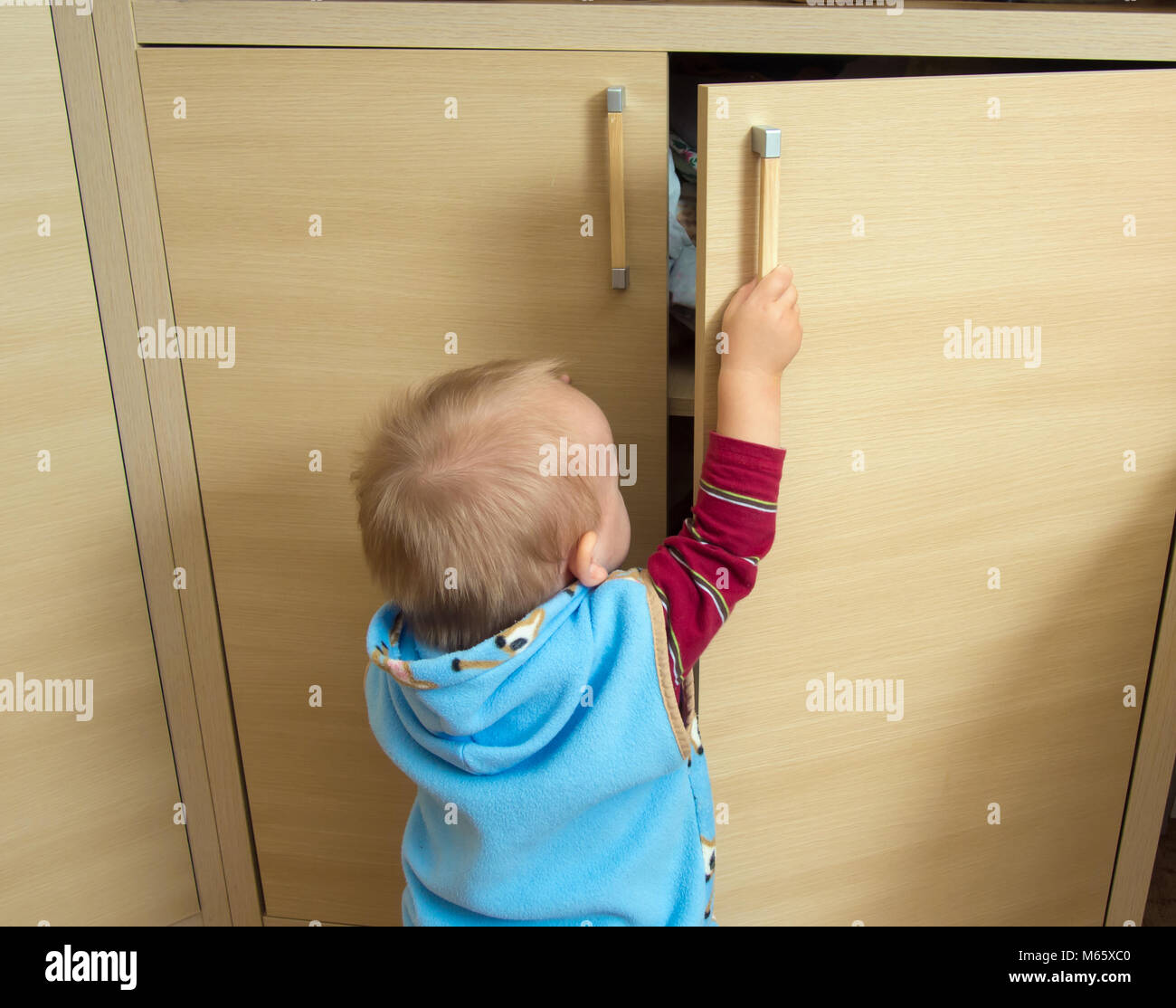 Little baby toddler opens the closet Stock Photo