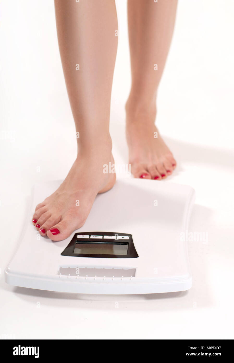 A woman standing on a weighing scale in white background with a lose weight  now note on its display Stock Photo - Alamy