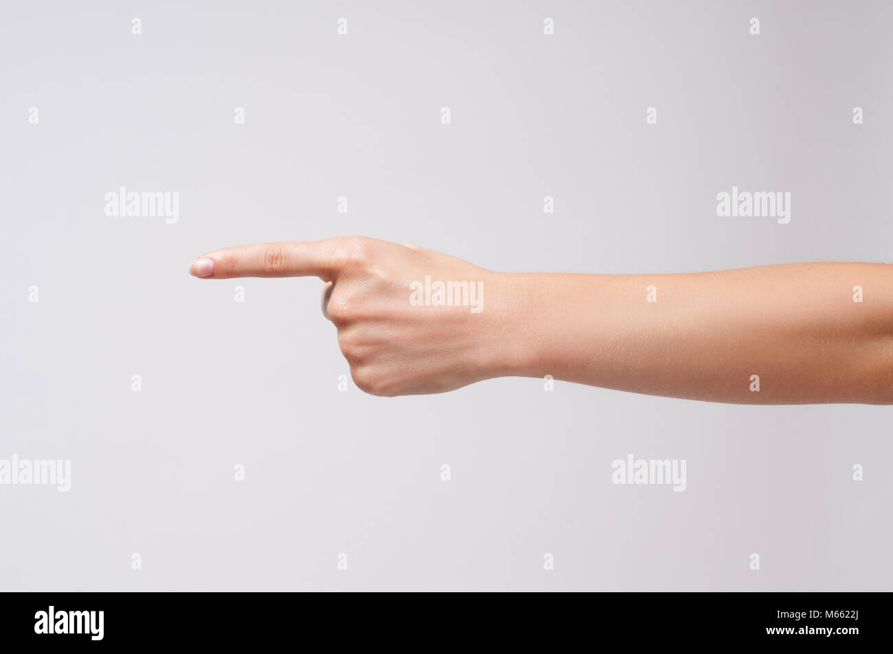 Woman's hand points a finger at something on white background. Stock Photo