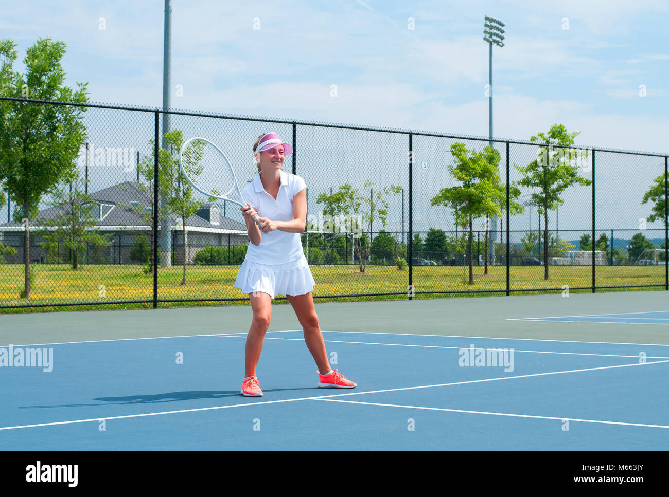 Girl in white sportswear stands on the tennis court near the net