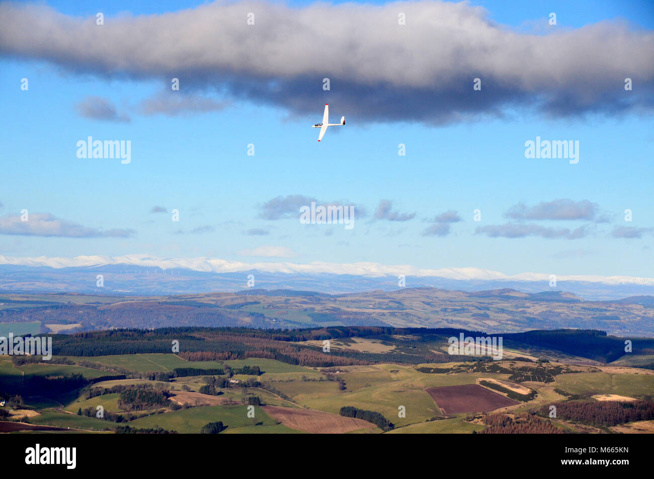 View from the hilltop of East Lomond in Fife looking inland towards the snow capped cairngorm mountains in the distance.  A glider flies close by.. Stock Photo
