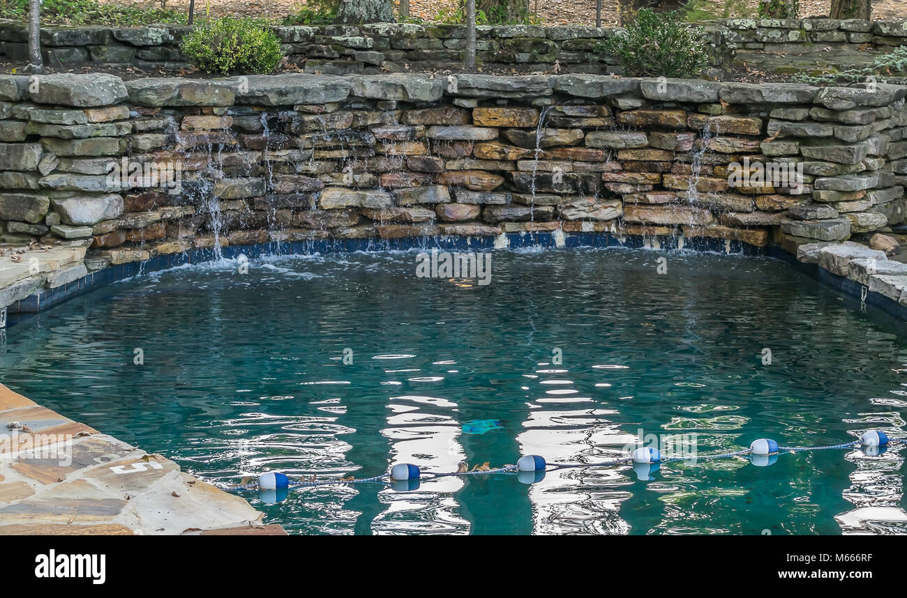 A small wading pool with a stone wall and falling water. Stock Photo
