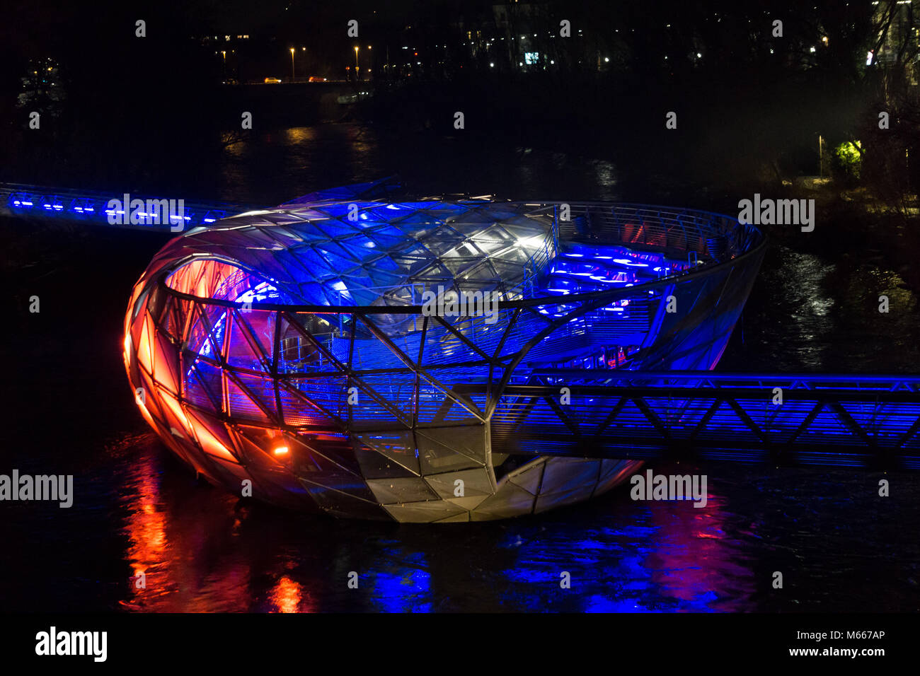 Graz, Austria - 08.02.2018: The famous Murinsel bridge lit up in red and blue colors at night Stock Photo