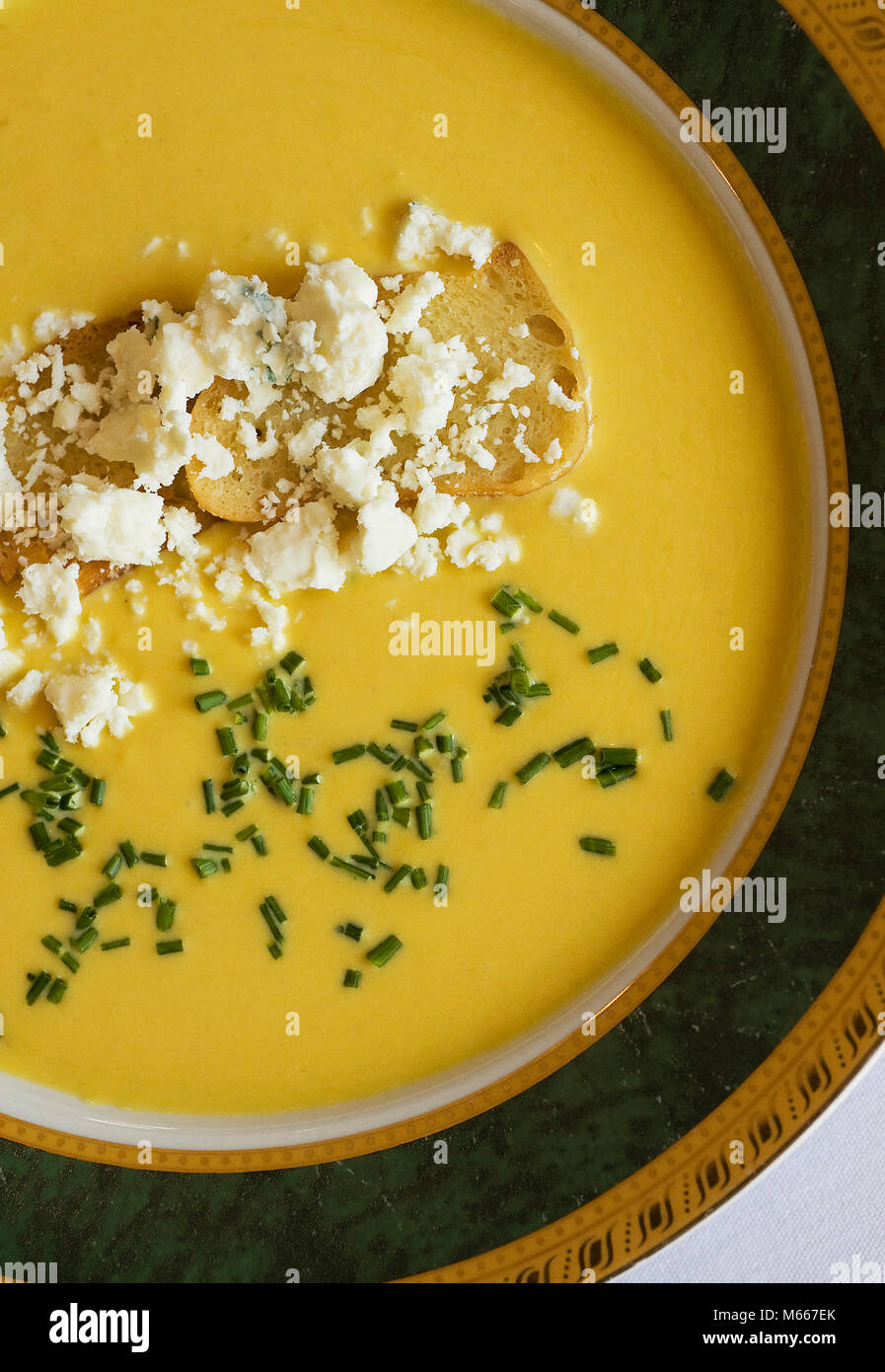 Butternut squash soup in a large decorative bowl with crumbled feta cheese photographed from directly overhead above view Stock Photo
