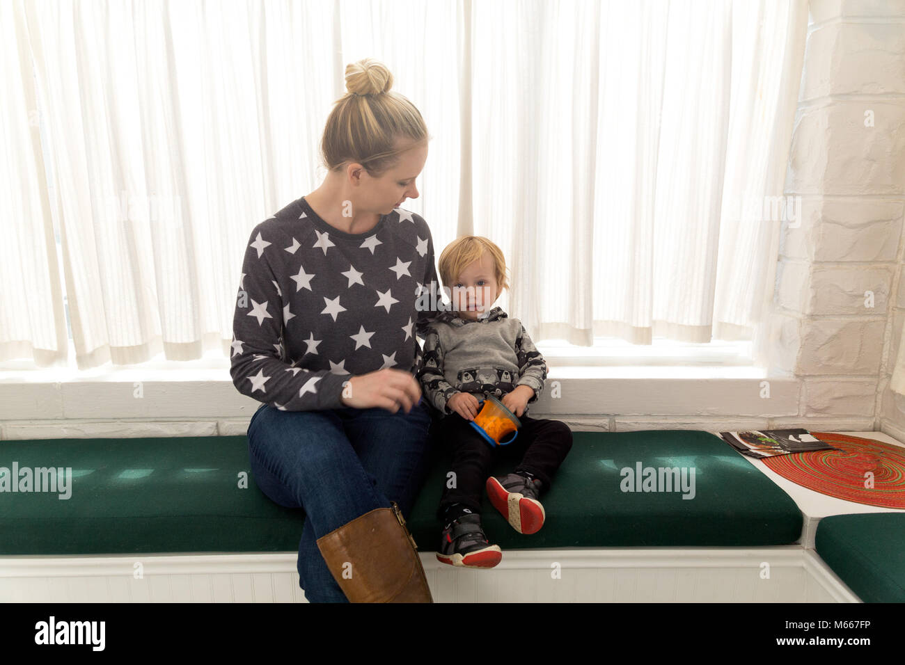 A Young Mom And Her Son Sit And Wait Patiently For The Little Boys