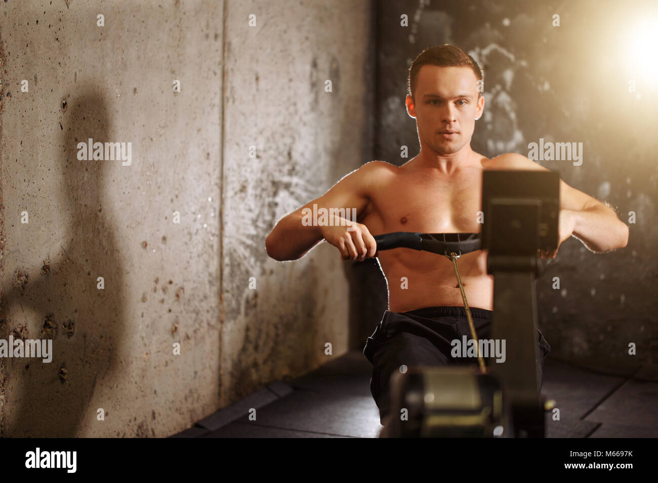 man training on row machine in gym Stock Photo
