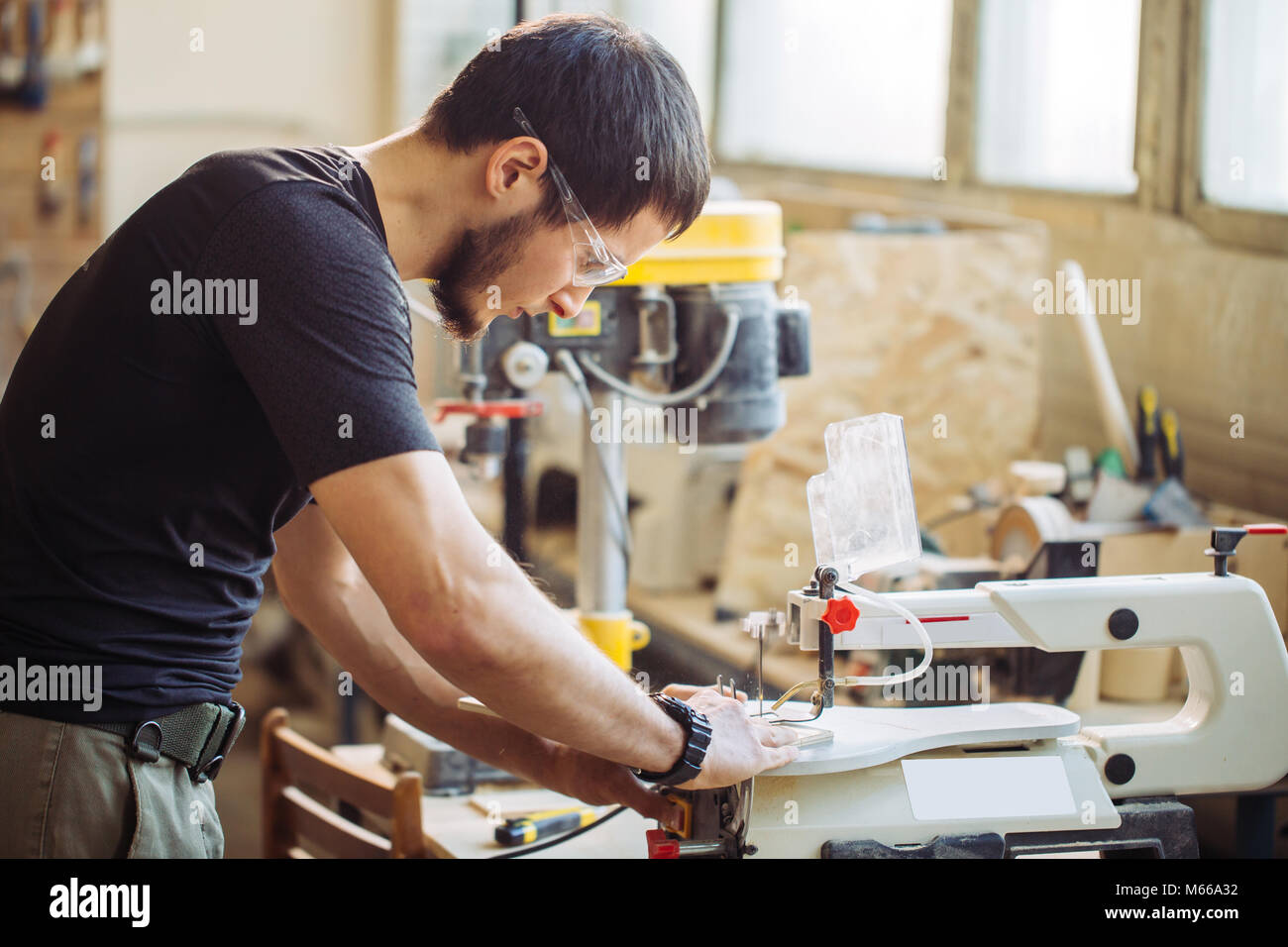 Carpenter engaged in processing wood at the sawmill. Stock Photo