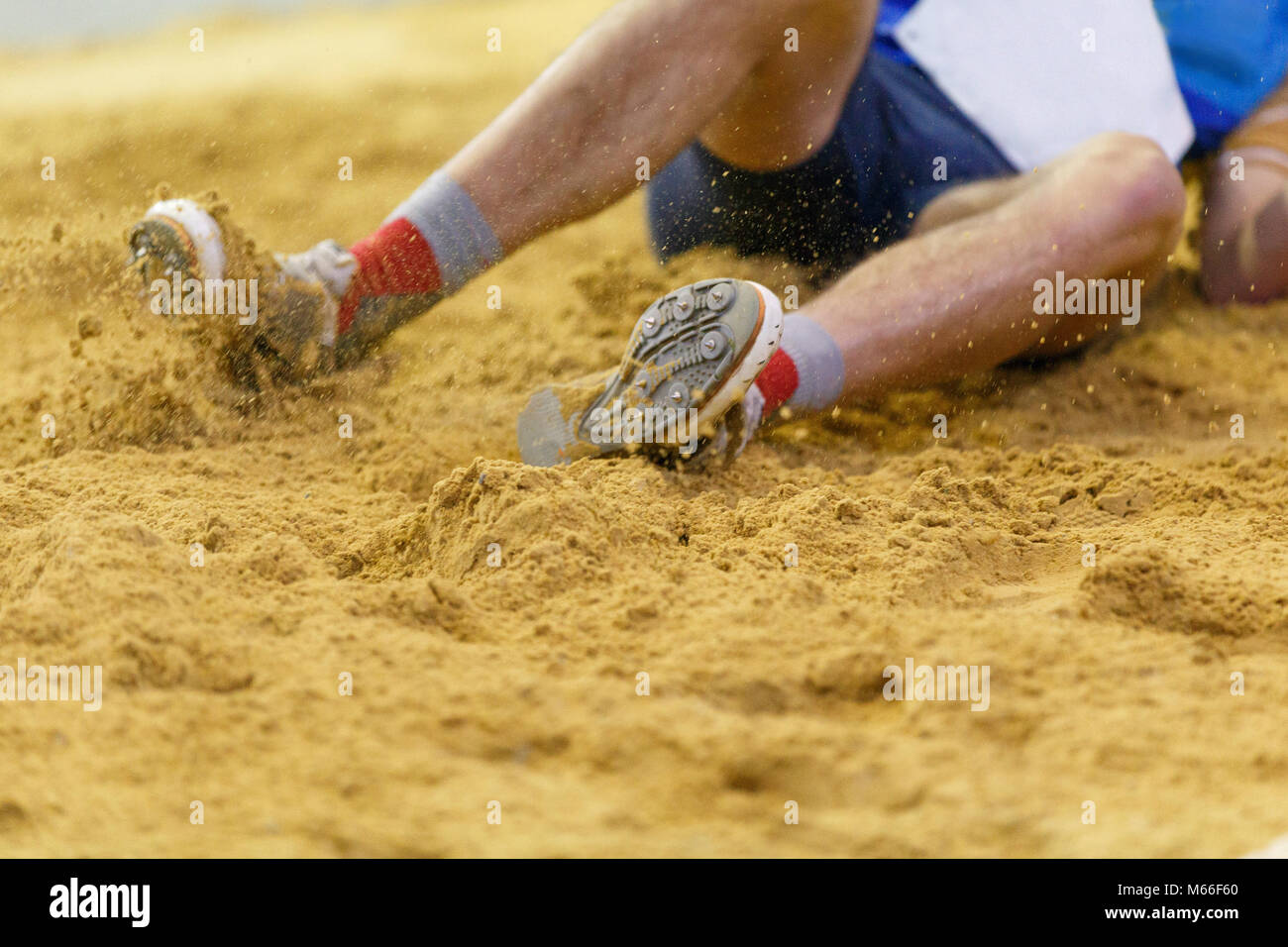 Sportsman landing into sandpit in long jump competition. Track and