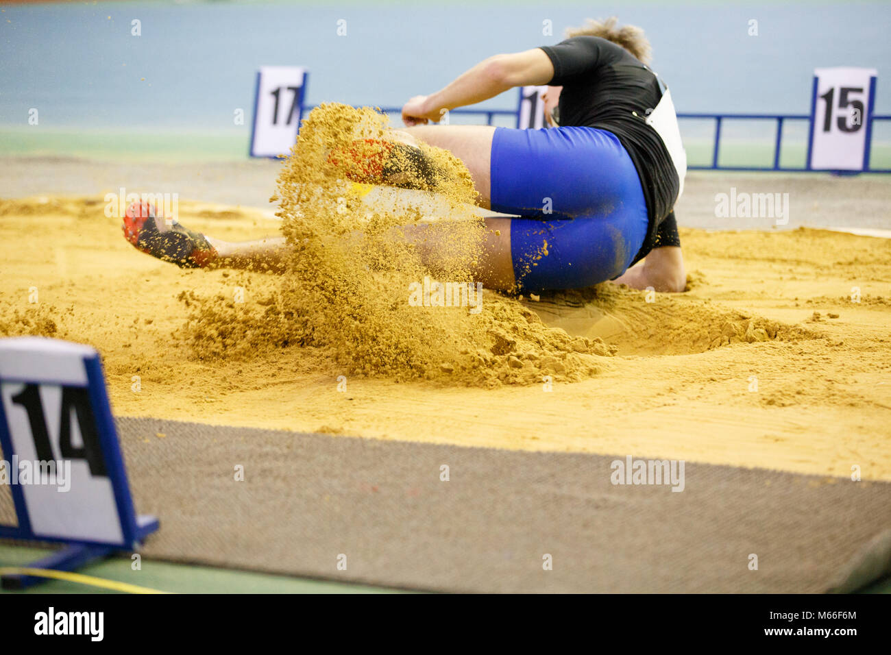 Sportsman landing into sandpit in long jump competition. Track and