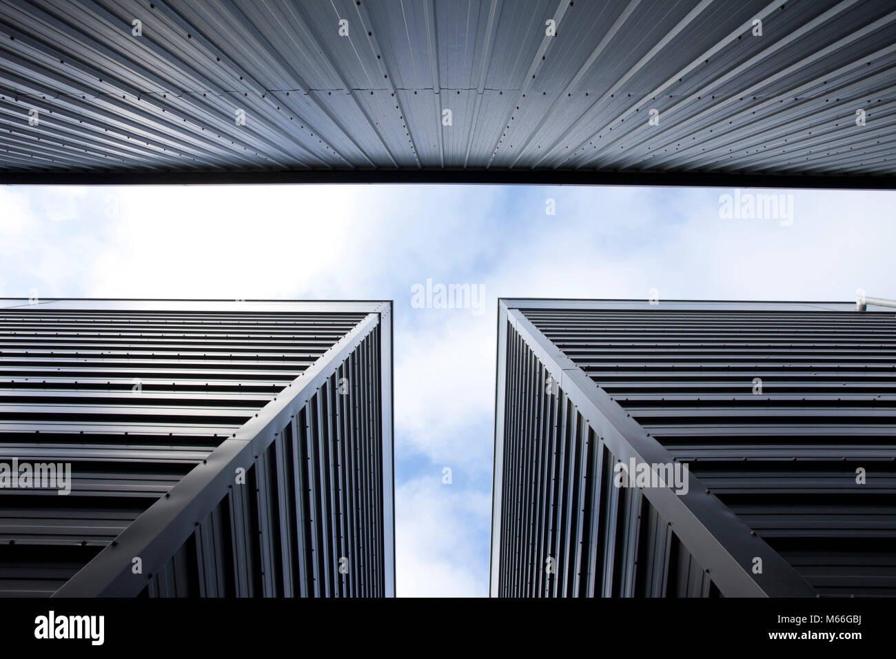 abstract view of steel cladding on modern warehousing locking up with sky with clouds an faint blue sky Stock Photo