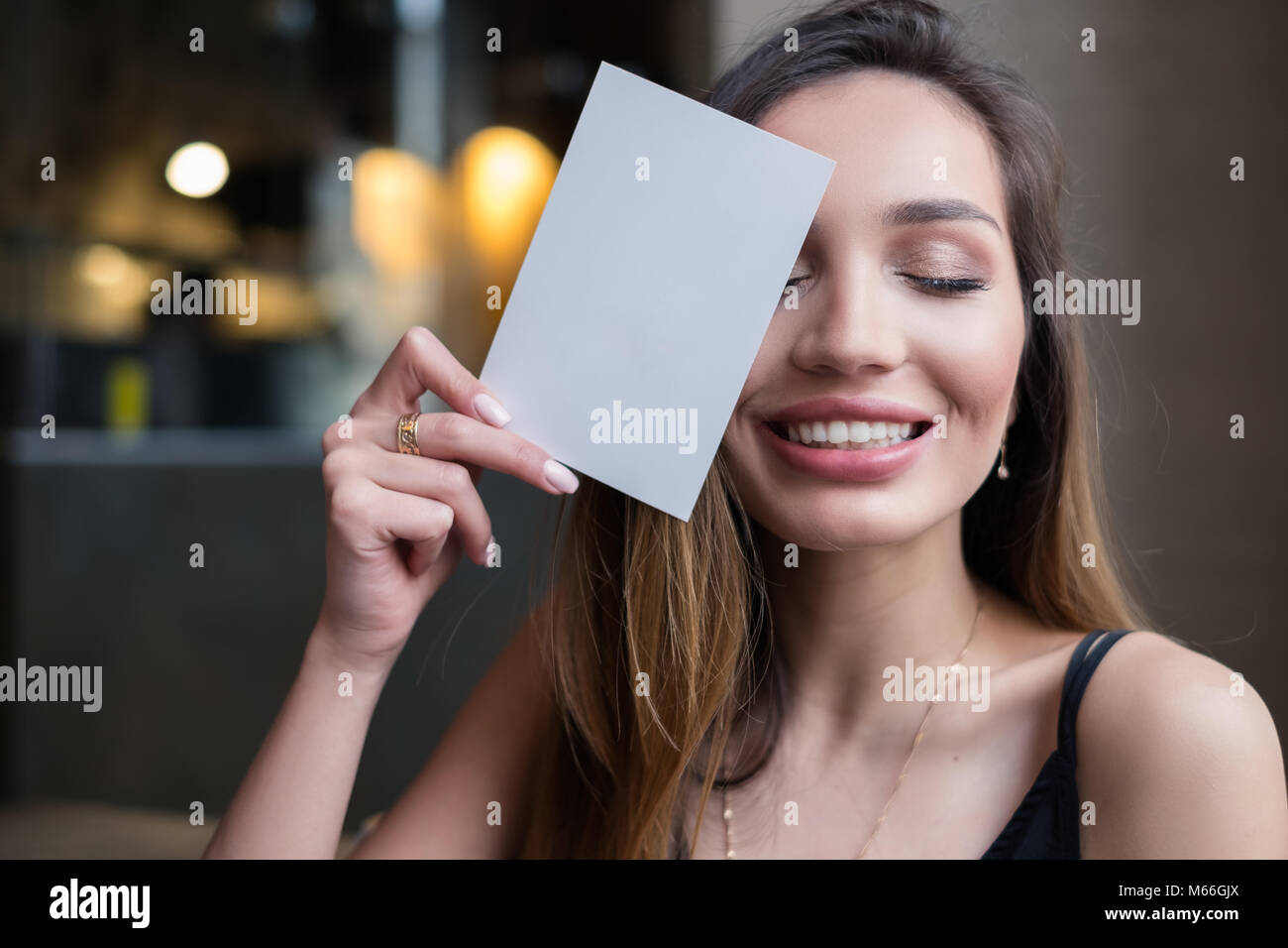 Smiling woman holding  blank card in front of her face Stock Photo