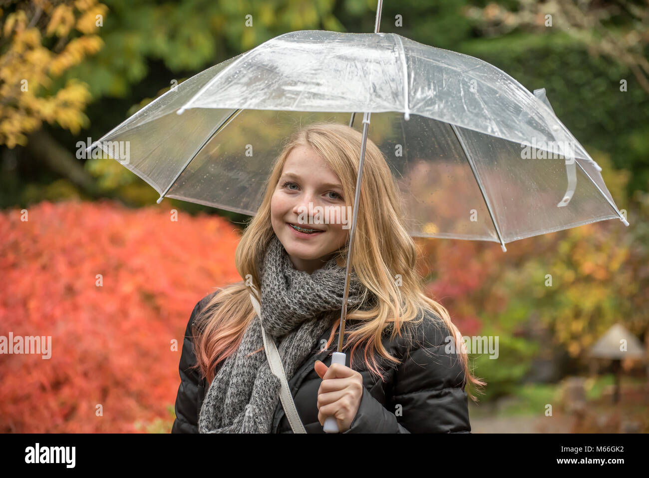 Smiling girl standing in the rain under an umbrella Stock Photo