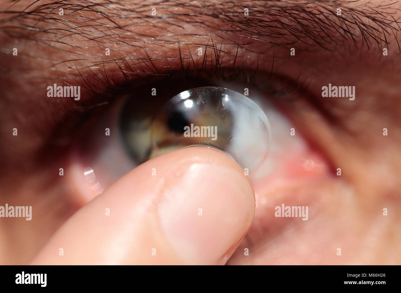Woman putting a contact lens in her eye Stock Photo