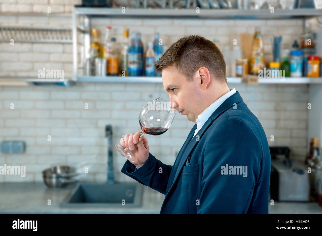 Winemaker or sommelier sniffs red wine in a glass on kitchen interior. tasting of red wine Stock Photo
