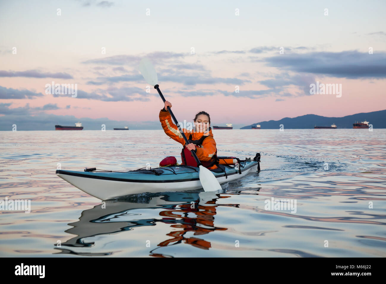 Adventurous woman is sea kayaking near Downtown Vancouver, British ...