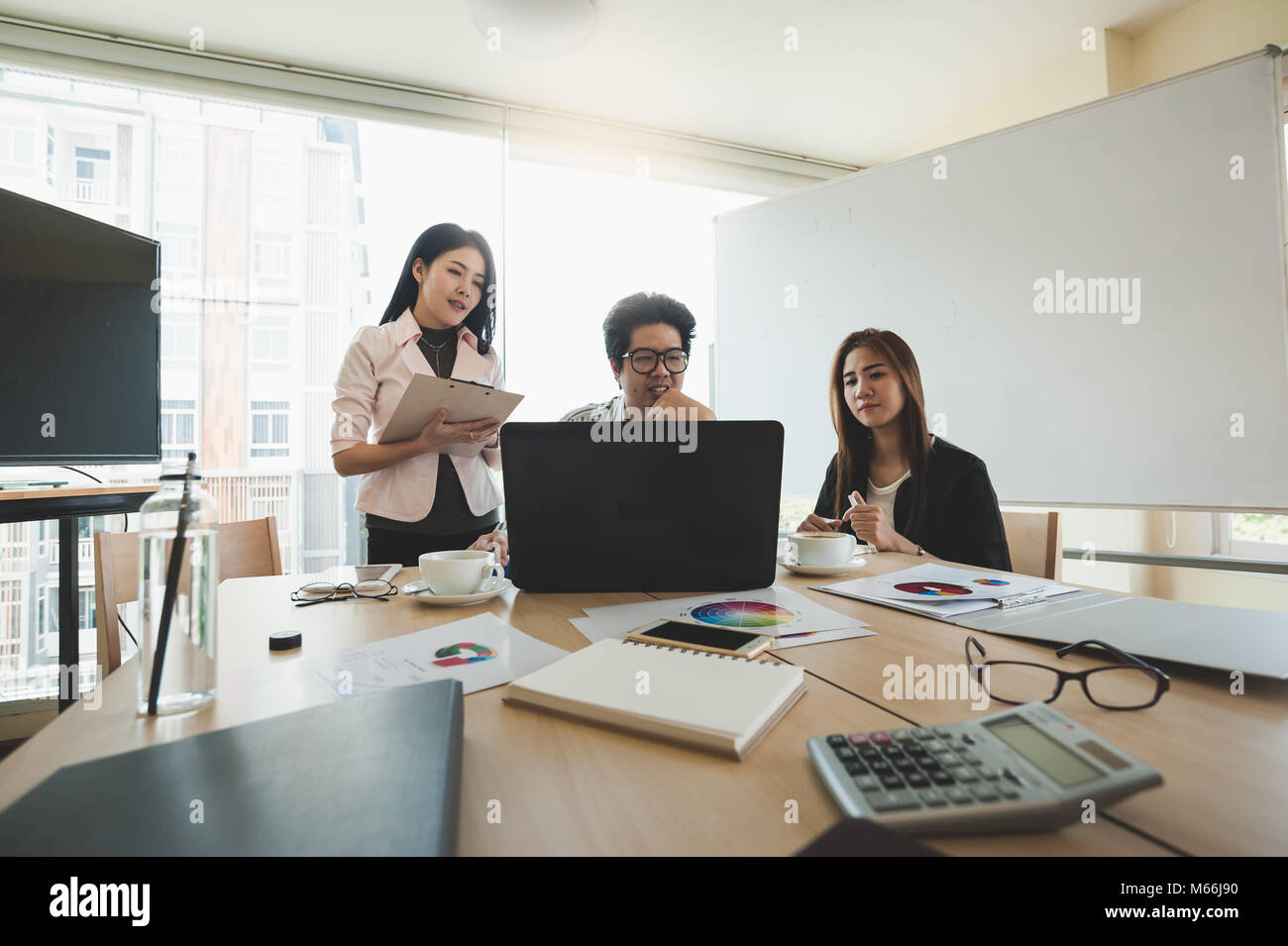 Young Asian businessman and businesswoman talking about their work in meeting room. Business team discussion planning and brainstorm in office conept. Stock Photo