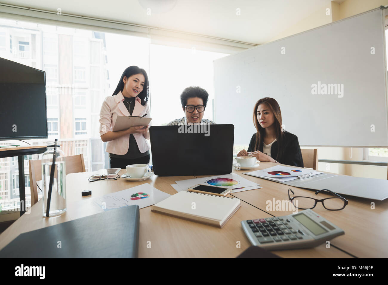 Young Asian businessman and businesswoman talking about their work in meeting room. Business team discussion planning and brainstorm in office conept. Stock Photo