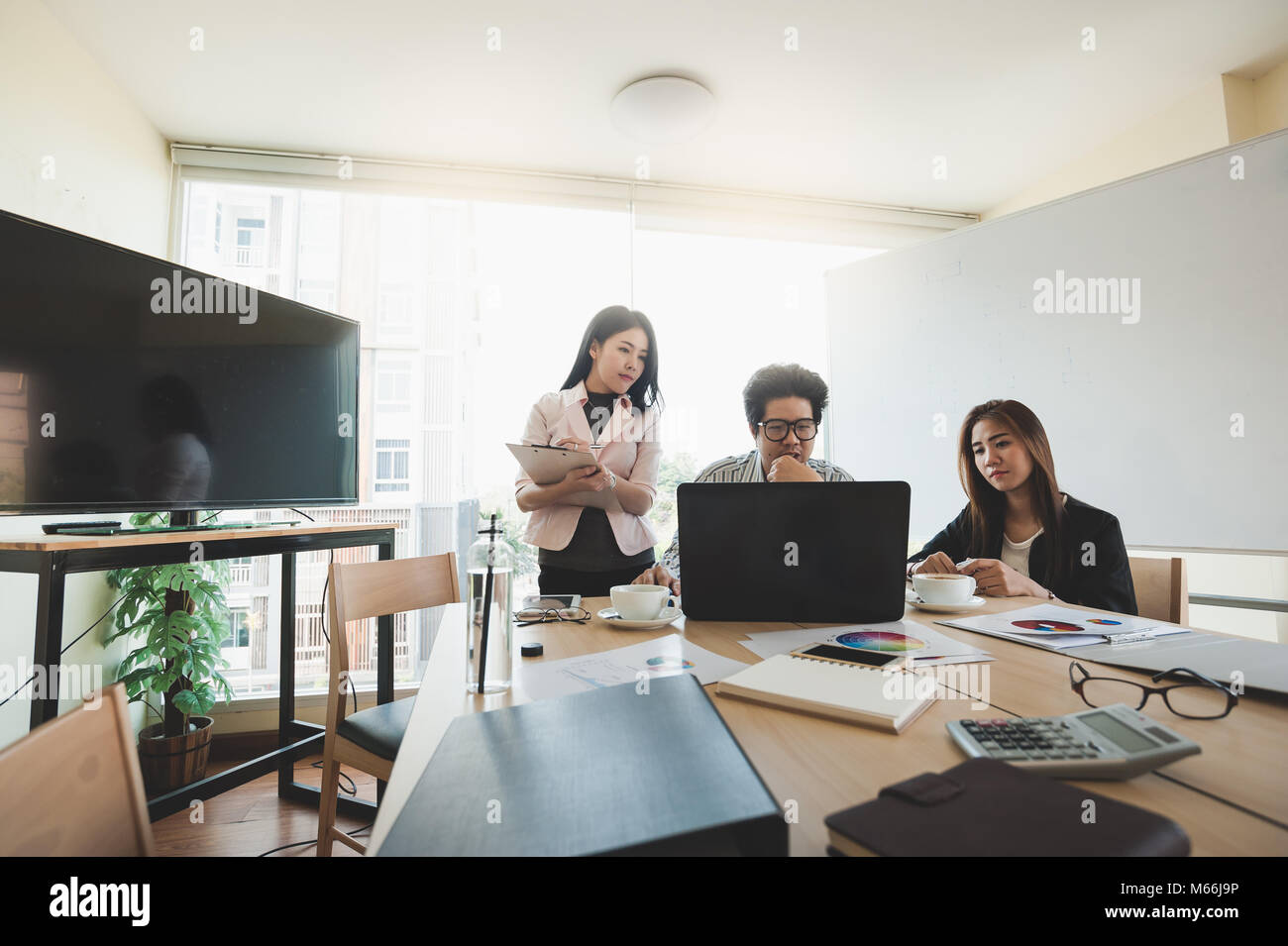 Young Asian businessman and businesswoman talking about their work in meeting room. Business team discussion planning and brainstorm in office conept. Stock Photo