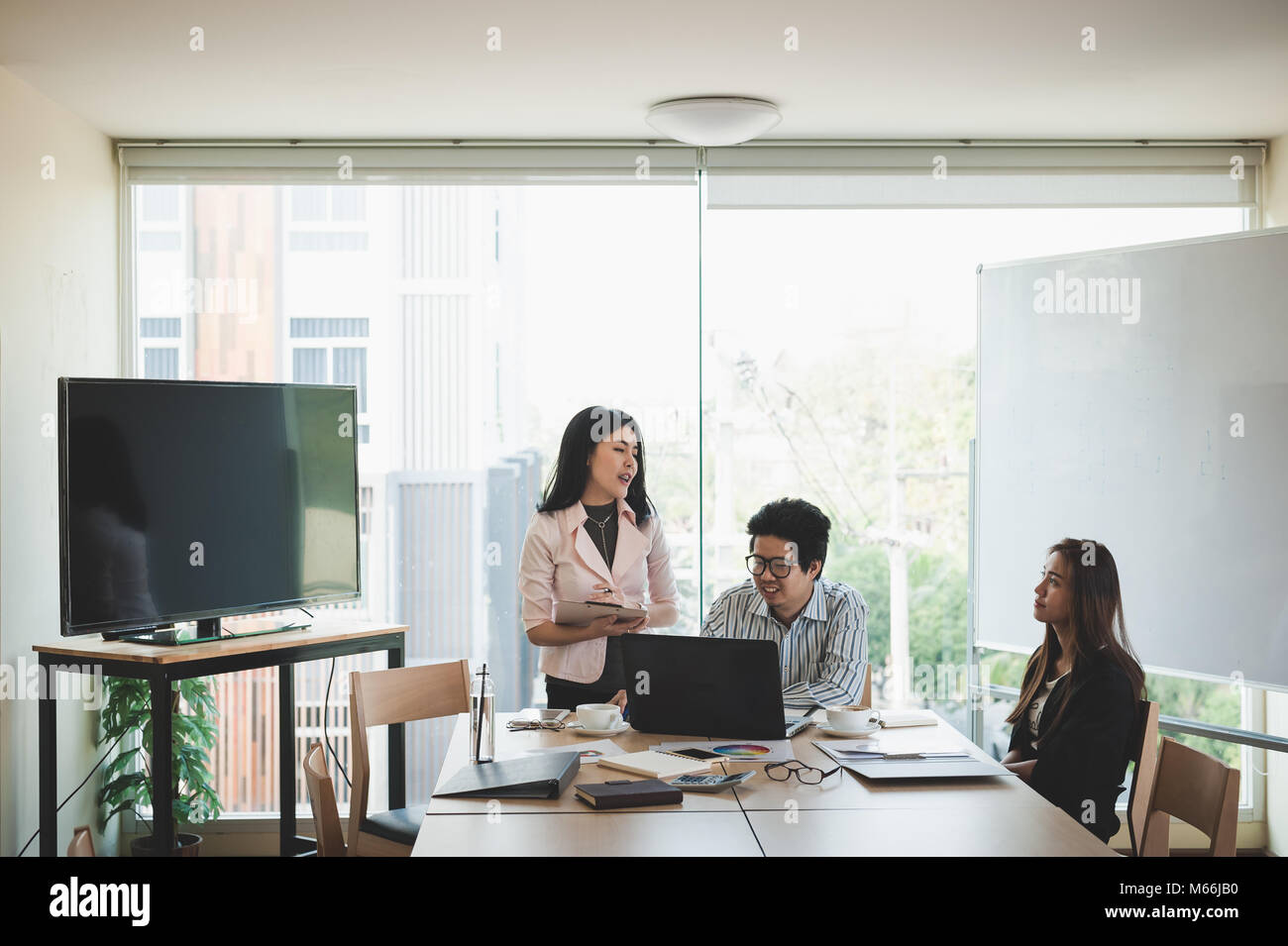 Young Asian businessman and businesswoman talking about their work in meeting room. Business team discussion planning and brainstorm in office conept. Stock Photo