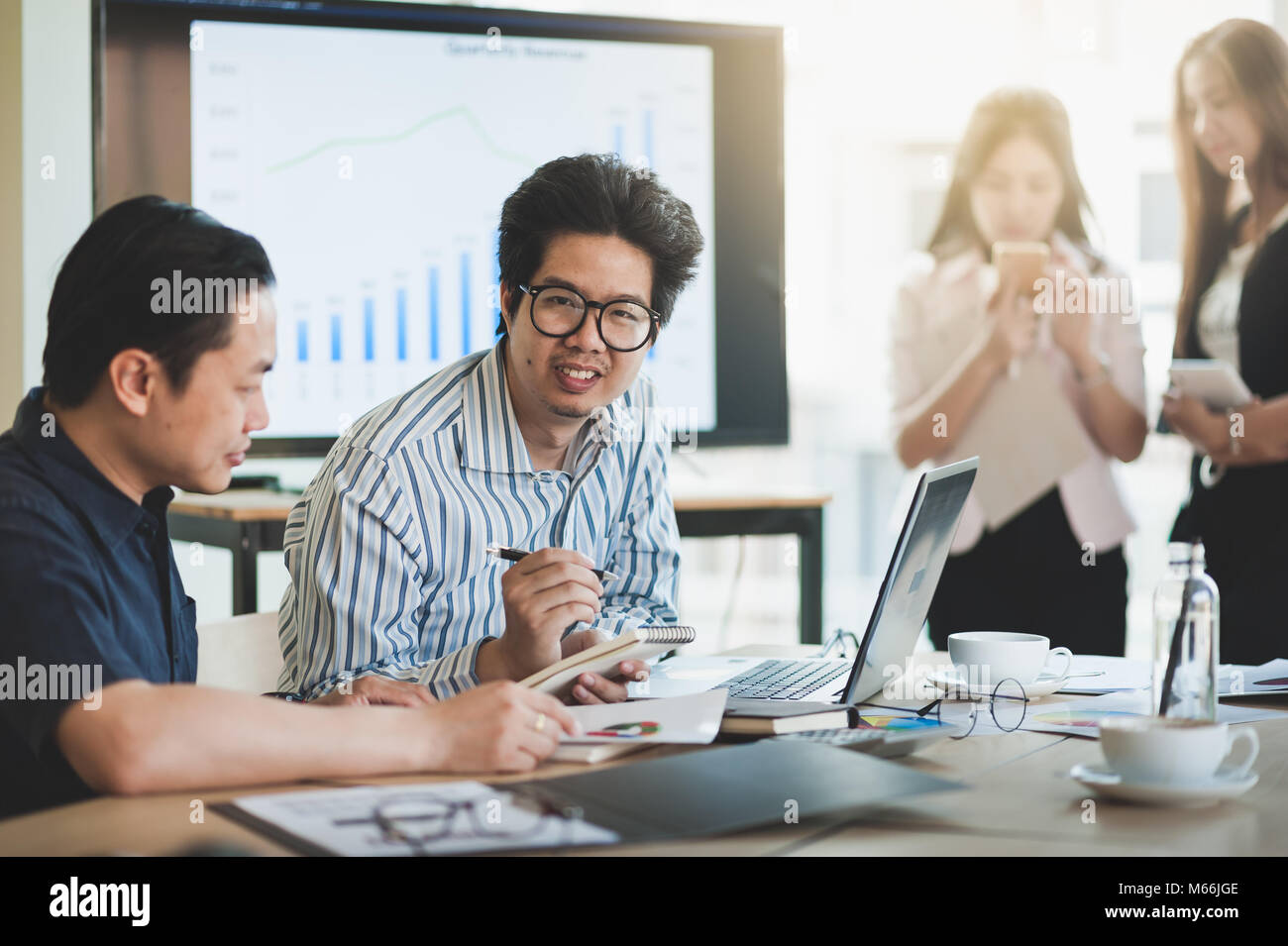 Asian businesspeople discussing and brainstorm with young freelance man in meeting room. Business company co-operate with outsource worker concept. Stock Photo