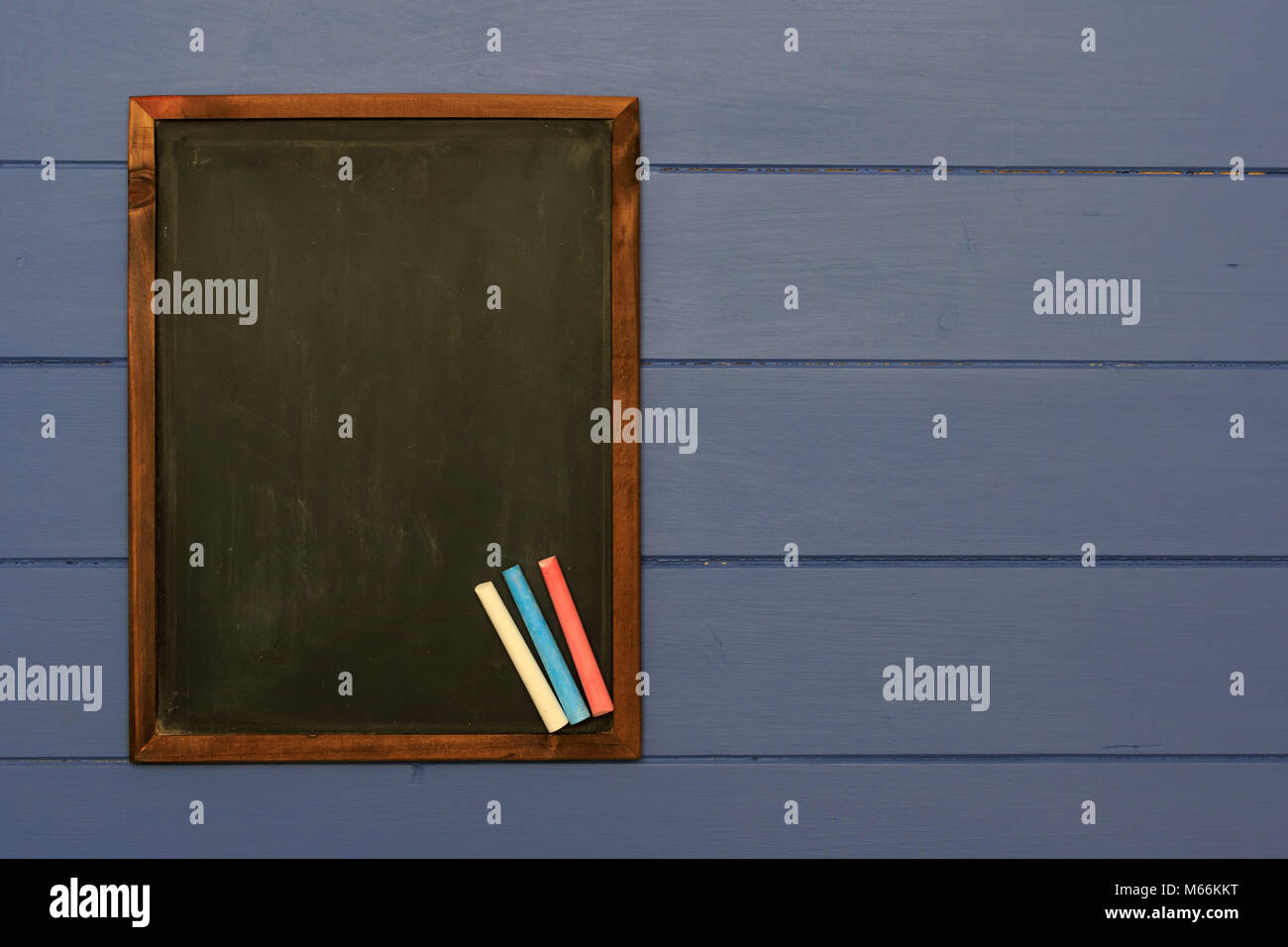 Slate chalk board with coloured chalk sticks on shabby blue board background Stock Photo
