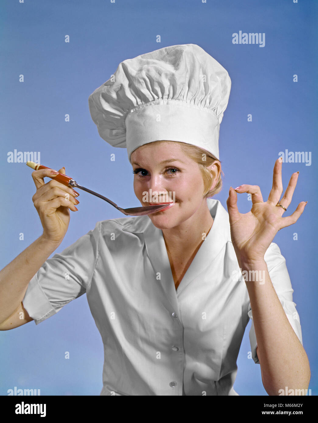 1960S WOMAN CHEF WEARING TOQUE LOOKING AT CAMERA TASTING FOOD MAKING OKAY SIGN SMILING - kf5637 HAR001 HARS GOOD OLD FASHION 1 STYLE COMMUNICATION CAREER BLOND SIGNAL INFORMATION CAUCASIAN TESTING LIFESTYLE SATISFACTION FEMALES JOBS STUDIO SHOT ONE PERSON ONLY COMMUNICATING COPY SPACE HALF-LENGTH LADIES OK INDOORS PROFESSION NOSTALGIA EYE CONTACT 25-30 YEARS 30-35 YEARS GOALS HOMEMAKER SINGLE OBJECT SKILL OCCUPATION HAPPINESS SKILLS HOMEMAKERS NOURISH CAREERS LEADERSHIP OKAY WORKFORCE TASTE TASTING AUTHORITY GESTURES SIGNALS SMILES APPROVAL COMMUNICATE COOKS NOURISHMENT O.K. MID-ADULT Stock Photo