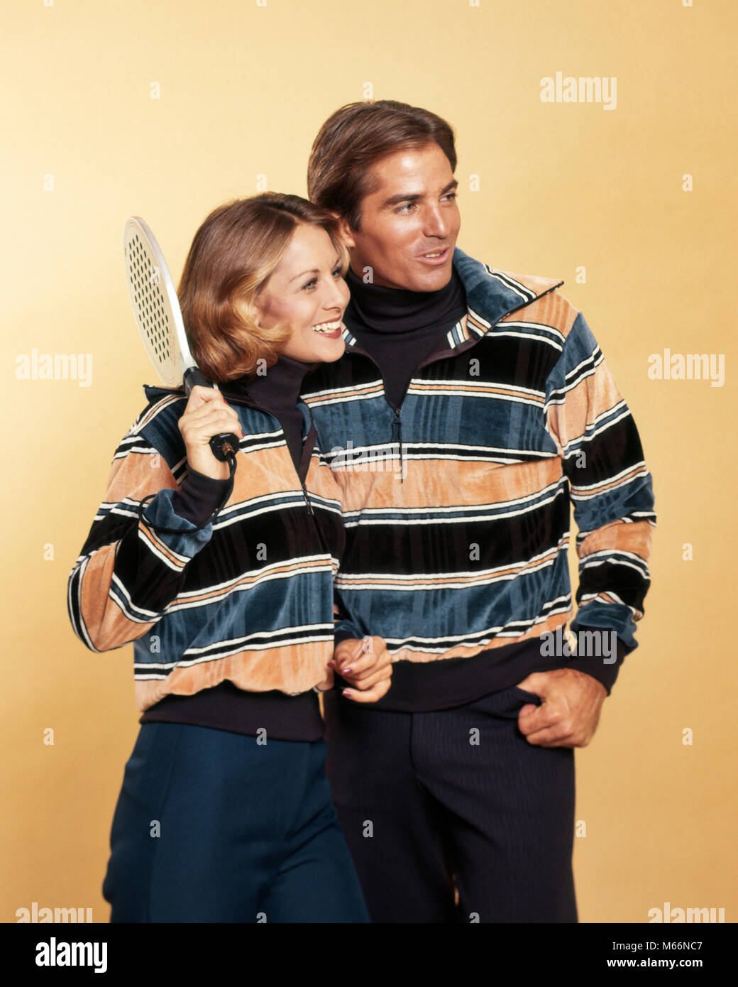 1970s SMILING COUPLE MAN WOMAN HOLDING SQUASH RACKET WEARING MATCHING STRIPED VELOUR PULLOVER SWEATERS FASHION SPORTSWEAR - ks14987 BAN001 HARS PLEASED JOY LIFESTYLE SATISFACTION STRIPED MARRIED SPOUSE HUSBANDS GROWNUP LUXURY SQUASH FRIENDSHIP HALF-LENGTH GROWN-UP CARING ATHLETIC COUPLES INDOORS CONFIDENCE NOSTALGIA TOGETHERNESS 20-25 YEARS 25-30 YEARS MATCHING SUCCESS WIVES HAPPINESS NOURISH CHEERFUL LEISURE STYLES RELAXATION CHOICE RECREATION PRIDE SMILES SWEATERS CONNECTION JOYFUL FASHIONS NOURISHMENT VELOUR YOUNG ADULT MAN YOUNG ADULT WOMAN CAUCASIAN ETHNICITY OLD FASHIONED PERSONS Stock Photo