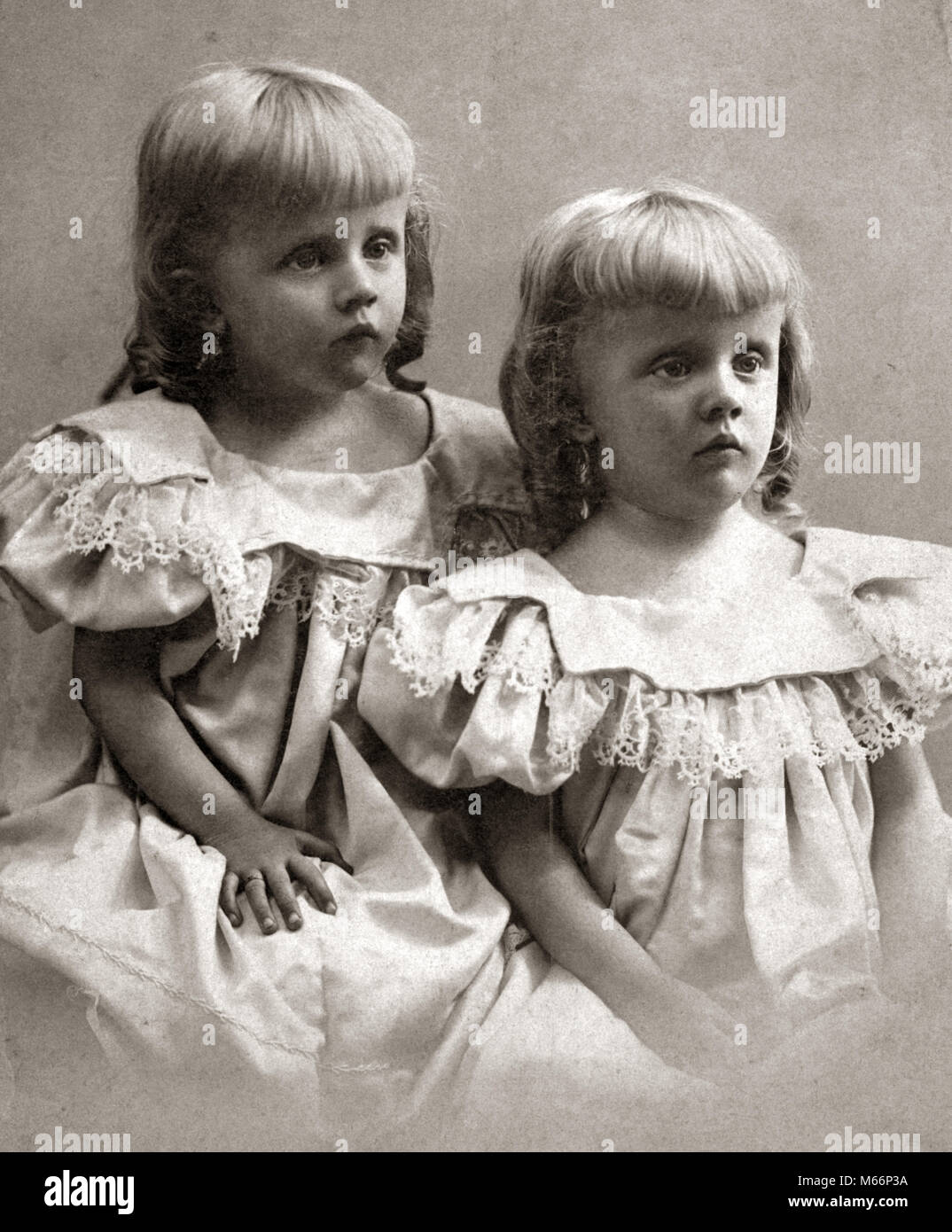 1890s PORTRAIT TURN OF THE 20TH CENTURY TWIN GIRLS SISTERS WEARING IDENTICAL DRESSES AND SHOWING MOROSE SAD FACIAL EXPRESSIONS - o4472 HAR001 HARS NOSTALGIA SADNESS TOGETHERNESS 1-2 YEARS 3-4 YEARS MATCHING SAME TURN OF THE 20TH CENTURY 1890s SIBLING CONNECTION ANONYMOUS LOOK-ALIKE DUPLICATE EMOTION EMOTIONAL EMOTIONS JUVENILES LOOK ALIKE B&W BLACK AND WHITE CAUCASIAN ETHNICITY CLONE MOROSE OLD FASHIONED Stock Photo
