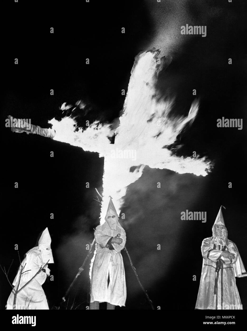 1930s HOODED MEMBERS OF KKK KU KLUX KLAN STANDING IN FRONT OF BURNING CROSS - q73548 CPC001 HARS SINGLE OBJECT PHYSICAL ROBES NATIONALISM SOCIETY AUTHORITY HOODED POLITICS SOUTHERN TERROR 1860s TERRORISM VIOLENT SMALL GROUP OF PEOPLE ORGANIZATION SUPREMACY BASED MALES MURDER RIGHT-WING TERRORIST ANTI-BLACK ANTI-IMMIGRANT ANTI-IMMIGRATION ANTI-JUDAISM ANTI-NEGRO ANTI-SEMITIC ANTI-SEMITISM ASSAULT B&W BLACK AND WHITE CAUCASIAN ETHNICITY EXTREMIST FAR RIGHT FIERY HATE HATEFUL HOODS INTOLERANCE INTOLERANT KKK KLAN KU KLUX KLAN OLD FASHIONED PERSONS RACISM RACIST REACTIONARY RECONSTRUCTION Stock Photo