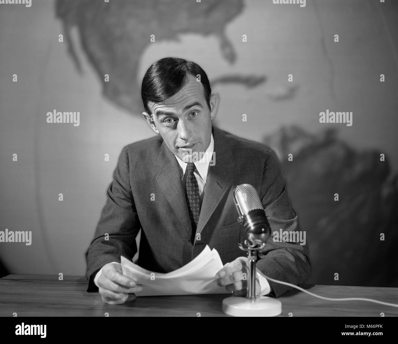 1960s 1970s NEWSMAN READING NEWS FROM PAPERS LOOKING AT CAMERA SPEAKING INTO MICROPHONE WORLD MAP BEHIND - r20836 HAR001 HARS ENTERTAINMENT CONFIDENCE JOURNALIST NOSTALGIA EYE CONTACT 25-30 YEARS 30-35 YEARS BROADCASTING ANNOUNCER AUTHORITY COMMUNICATE REPORTING COMMUNICATIONS JOURNALISM MALES MID-ADULT MID-ADULT MAN NEWSMAN ANNOUNCING B&W BLACK AND WHITE CAUCASIAN ETHNICITY LOOKING AT CAMERA NEWSCAST NEWSROOM OCCUPATIONS OLD FASHIONED PERSONS REPORTAGE Stock Photo