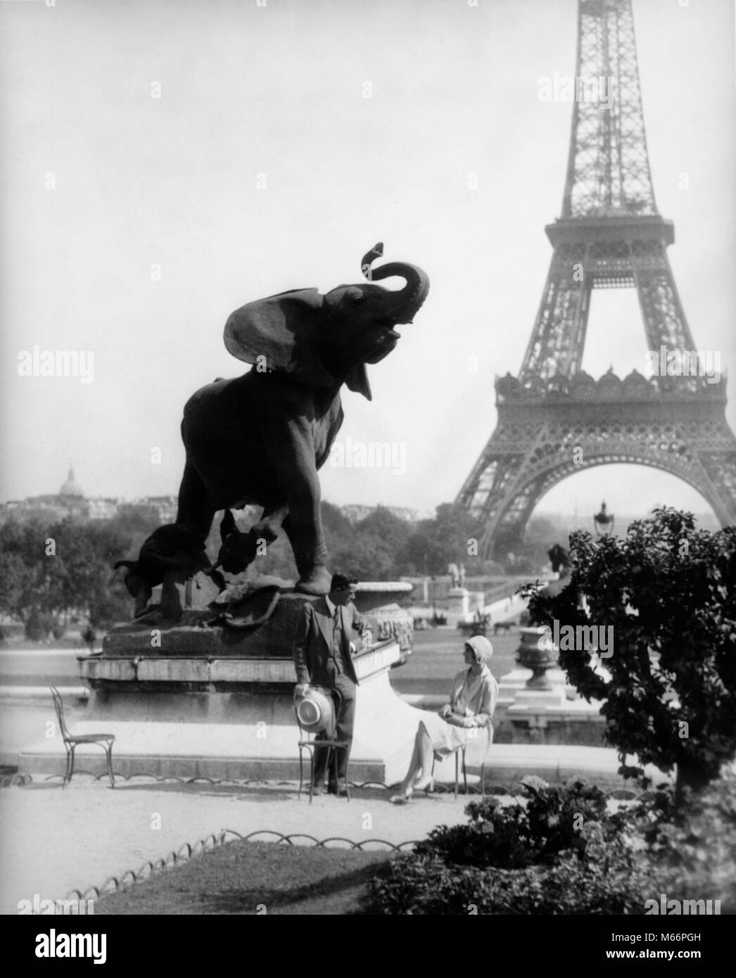 1920s COUPLE MAN WOMAN ELEPHANT STATUE GARDEN OF TROCADERO WITH EIFFEL TOWER IN BACKGROUND PARIS FRANCE - r4347 HAR001 HARS HUSBANDS LUXURY COPY SPACE FRIENDSHIP LADIES ANIMALS COUPLES NOSTALGIA EUROPE TOGETHERNESS 20-25 YEARS 25-30 YEARS 30-35 YEARS EIFFEL TOWER WIVES ADVENTURE CAPITOL EUROPEAN STYLES TOURIST RELATIONSHIPS CAPITAL FASHIONS CITIES MALES MID-ADULT MID-ADULT MAN MID-ADULT WOMAN B&W BLACK AND WHITE OLD FASHIONED PERSONS TROCADERO Stock Photo