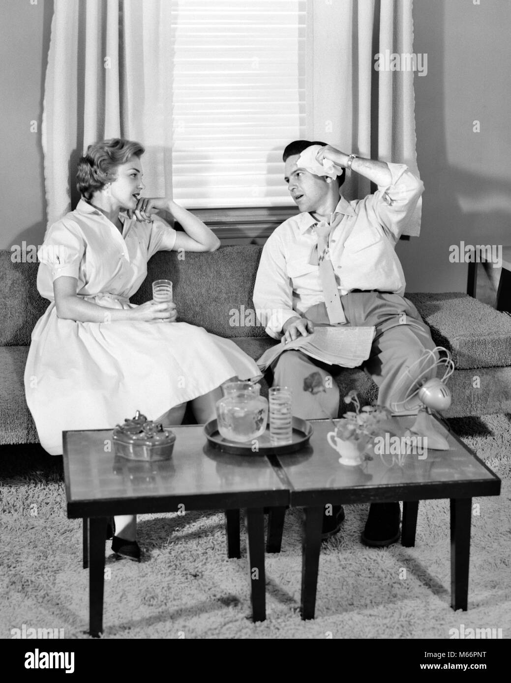 1950s COUPLE SITTING ON LIVING ROOM COUCH TRYING TO COOL DOWN DRINKING ICED DRINK BEFORE FAN ON COFFEE TABLE - s5601 HAR001 HARS COPY SPACE FULL-LENGTH LADIES FAN COUPLES INDOORS SWEAT ICED NOSTALGIA SWEATING SUMMERTIME 30-35 YEARS 35-40 YEARS BEFORE TEMPERATURE WIVES LIVING ROOM TRYING UNCOMFORTABLE SOLUTIONS COOL DOWN MALES MID-ADULT MID-ADULT MAN MID-ADULT WOMAN B&W BLACK AND WHITE CAUCASIAN ETHNICITY COFFEE TABLE HEAT WAVE HUMID OLD FASHIONED OPPRESSIVE OVER HEATED OVERHEATED PERSONS PERSPIRING SWELTERING WIPING FACE Stock Photo