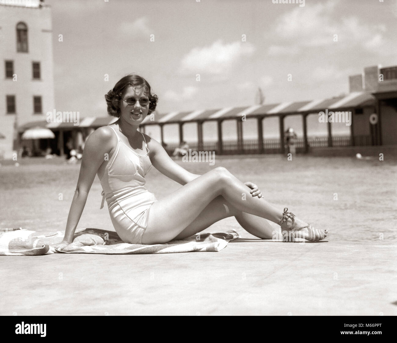 1930s WOMAN SITTING POOL SIDE LOOKING AT CAMERA WEARING FASHIONABLE SUNGLASSES BATHING SUIT AND SANDALS MIAMI BEACH FLORIDA USA - s9100 HAR001 HARS STYLE TROPICAL BATHING YOUNG ADULT VACATION CAUCASIAN WEAR LIFESTYLE FEMALES SWIM GROWNUP ONE PERSON ONLY UNITED STATES COPY SPACE FULL-LENGTH LADIES GROWN-UP UNITED STATES OF AMERICA NOSTALGIA NORTH AMERICA EYE CONTACT NORTH AMERICAN OCCUPATION URBAN CENTER SWIMMING POOL LEISURE RELAXATION RECREATION WATER RECREATION SOUTHEAST OCCASION POSING SOUTHERN EAST COAST SANDY POOL SIDE GULF COAST SWIM WEAR FL MODELING POOL-SIDE SANDALS YOUNG ADULT WOMAN Stock Photo