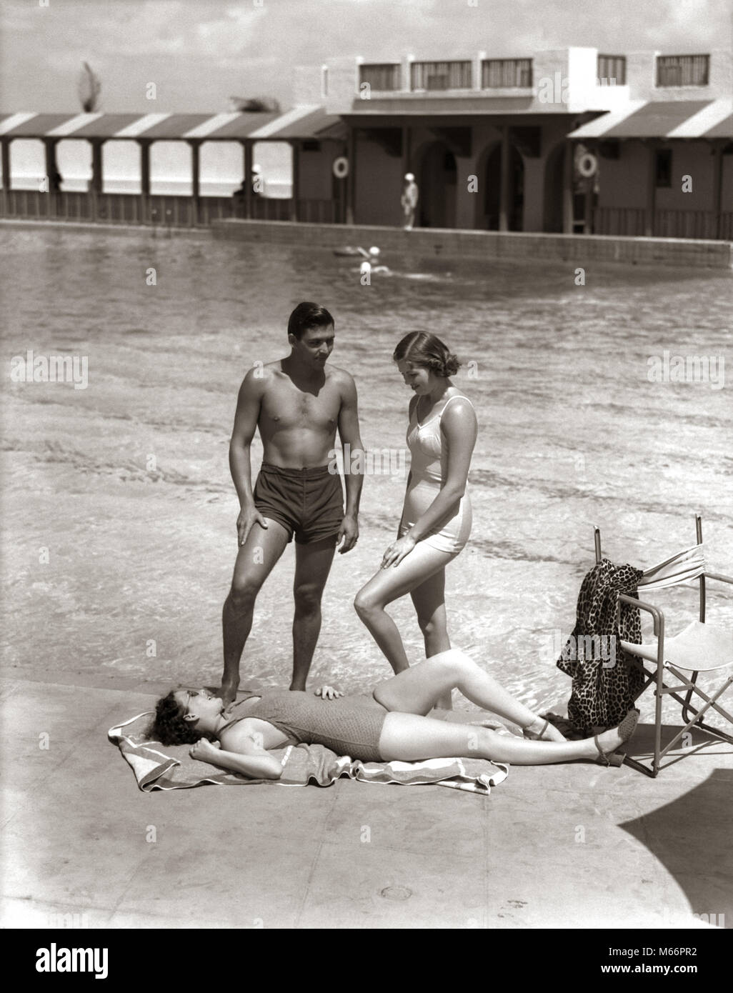1930s 1940s TWO WOMEN SUNBATHING AND MAN AT HOTEL SWIMMING POOL SIDE WEARING BATHING SUITS VACATION MIAMI BEACH FLORIDA USA - s9286 HAR001 HARS SWIMMER TROPICAL BATHING YOUNG ADULT LEOPARD SUITS VACATION CAUCASIAN WEAR LIFESTYLE ROBE SWIM GROWNUP HEALTHINESS UNITED STATES COPY SPACE FRIENDSHIP FULL-LENGTH GROWN-UP SUNBATHING NOSTALGIA NORTH AMERICA TOGETHERNESS NORTH AMERICAN URBAN CENTER SWIMMING POOL LEISURE RELAXATION RECREATION WATER FELINE RECREATION SOUTHEAST SOUTHERN EAST COAST SANDY POOL SIDE SMALL GROUP OF PEOPLE GULF COAST CREATURE FL LARGE CAT MAMMAL POOL-SIDE YOUNG ADULT MAN Stock Photo
