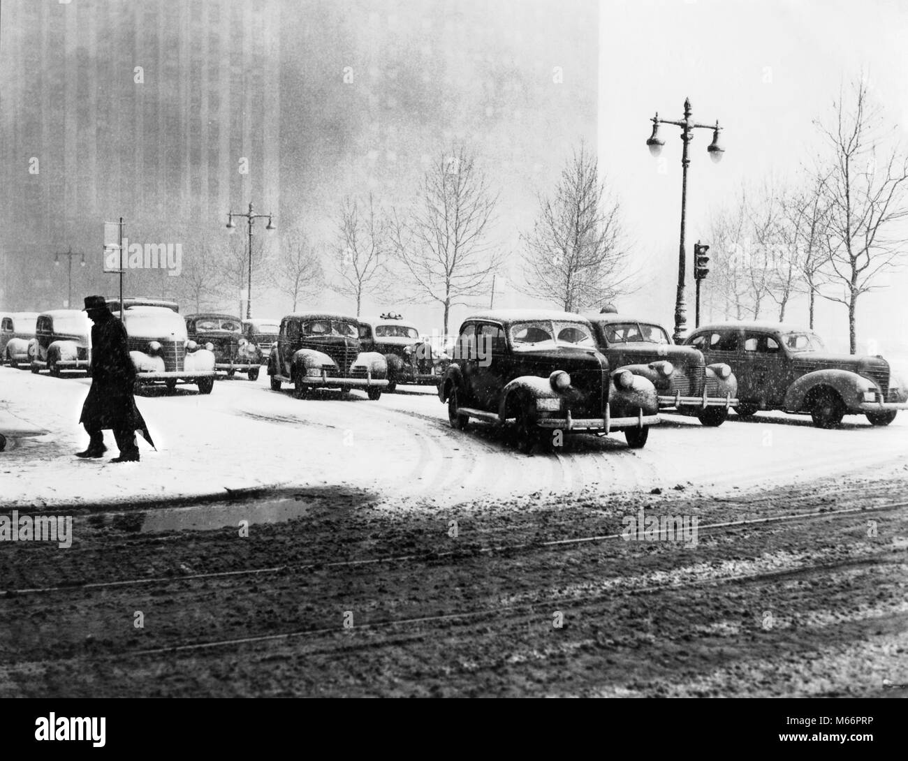 1940s ANONYMOUS SILHOUETTED PEDESTRIAN CROSSING CITY STREET IN WINTER WITH SNOW ON ROAD AND CAR TRAFFIC NYC NEW YORK USA - t762 HAR001 HARS 30-35 YEARS 35-40 YEARS 40-45 YEARS WINTER SEASON PEDESTRIAN URBAN CENTER SILHOUETTED AUTOS GOTHAM NYC SLUSH NEW YORK SEASON AUTOMOBILES CITIES MOBILITY VEHICLES WALKER NEW YORK CITY ANONYMOUS MID-ADULT MID-ADULT MAN B&W BLACK AND WHITE OLD FASHIONED PERSONS Stock Photo