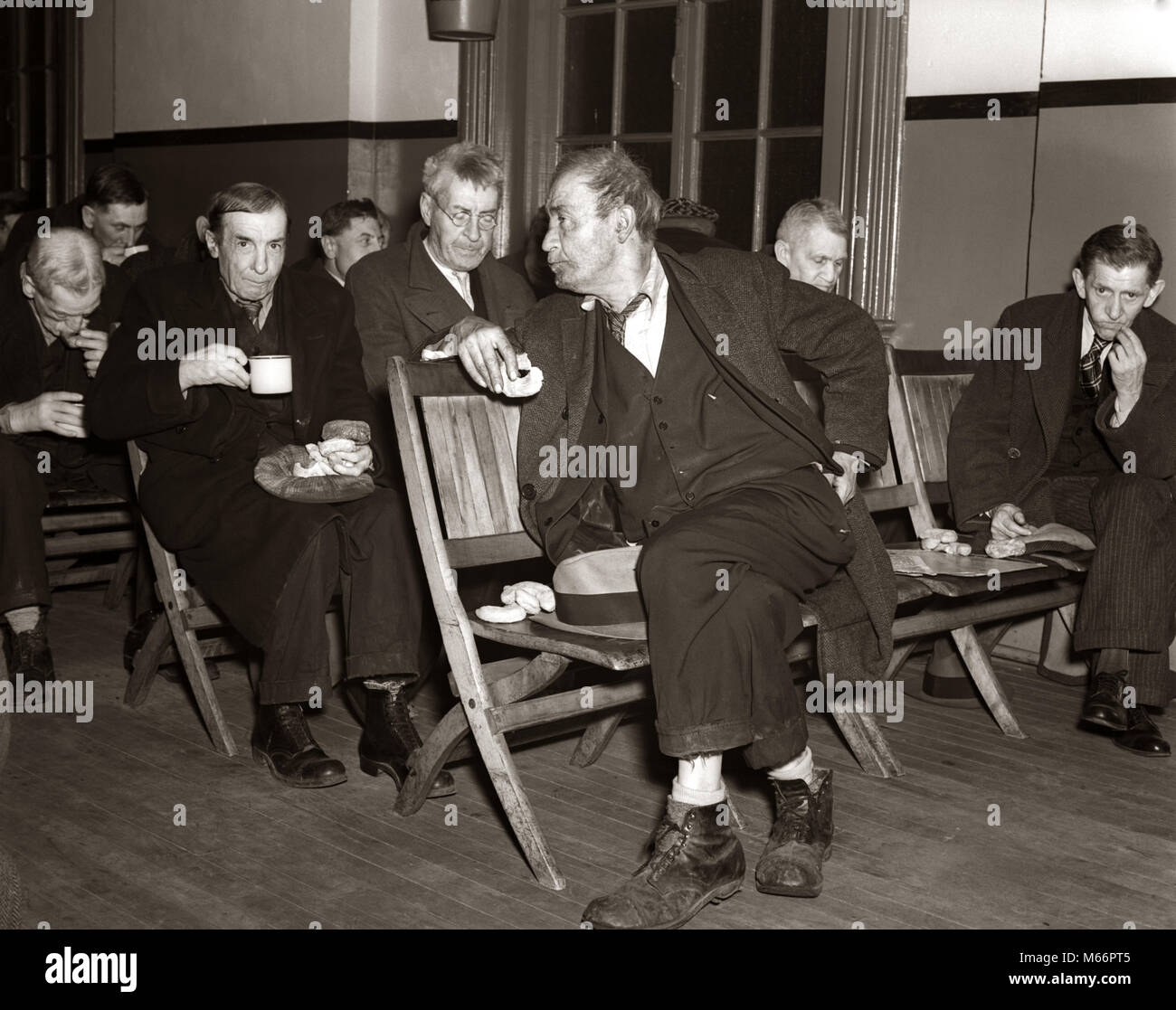 1930s During Great Depression Unemployed Men Sitting In Room On Wooden Chairs Drinking Coffee