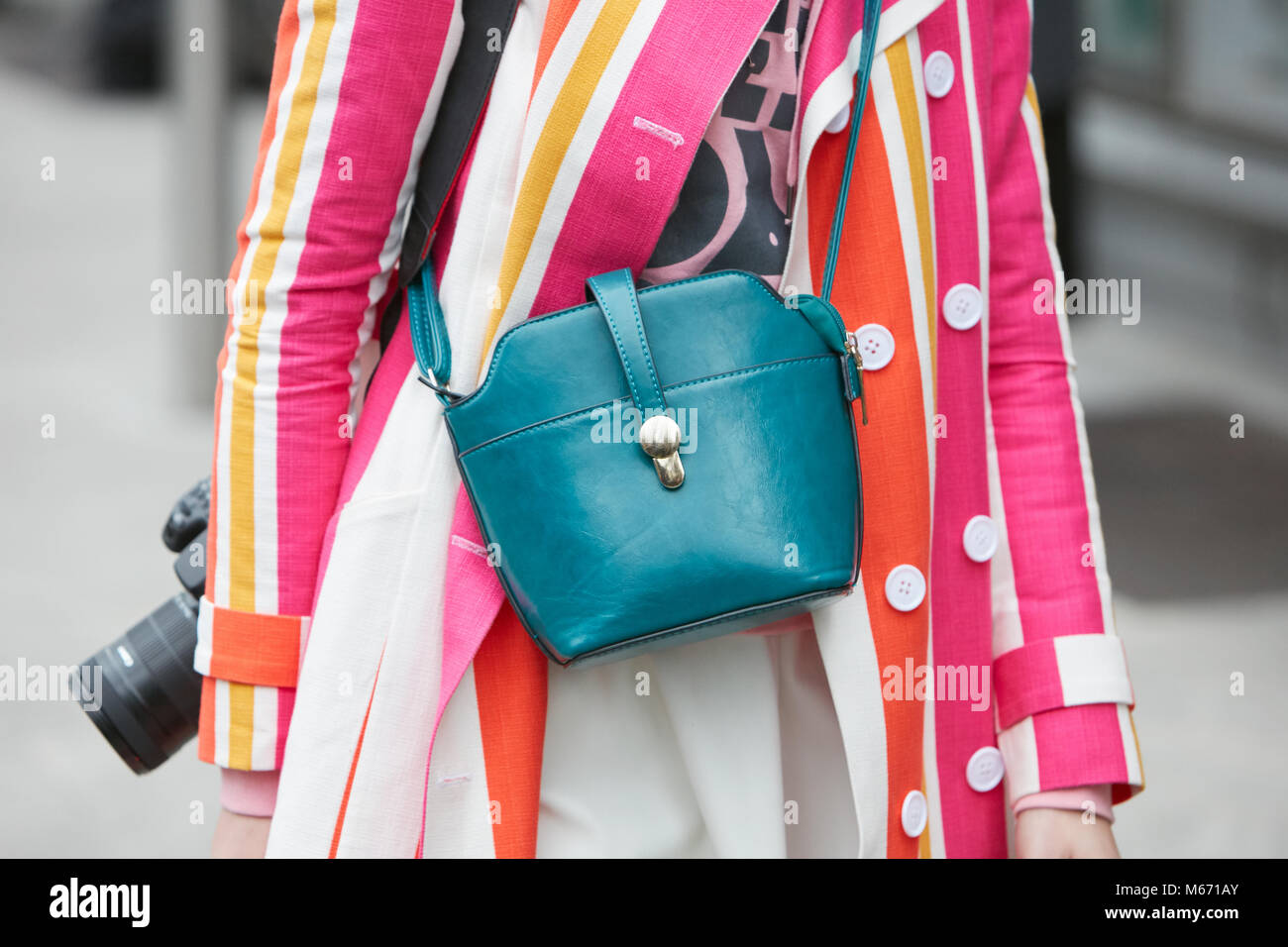 MILAN - FEBRUARY 25: Woman photographer with pink, white, yellow and orange striped jacket and blue leather bag before Emporio Armani fashion show, Mi Stock Photo