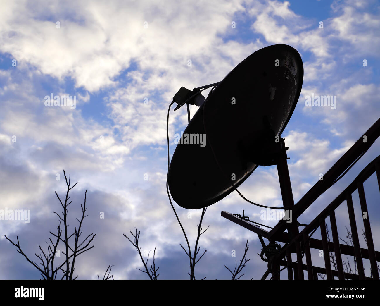 Silhouette of home satellite dish antenna on the balcony with cloudy blue sky Stock Photo