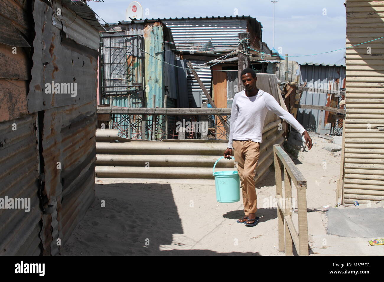 09 February 2018, South Africa, Cape Town, Khayelitsha: Anele Goba, 34, who lives in the Khayelitsha slum area outside Cape Town, has to carry water from a communal tap to his hut every day. He has little sympathy for the middle class, who fears 'zero hour', when Cape Town has to turn off the water due to a drought. Photo: Kristin Palitza/dpa Stock Photo